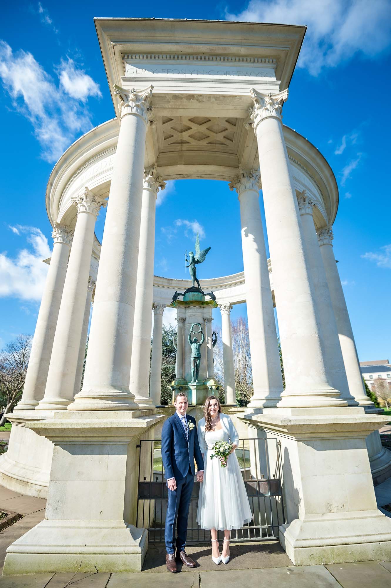 Bride and groom posing in front of the Alexandra Gardens memorial in Cardiff