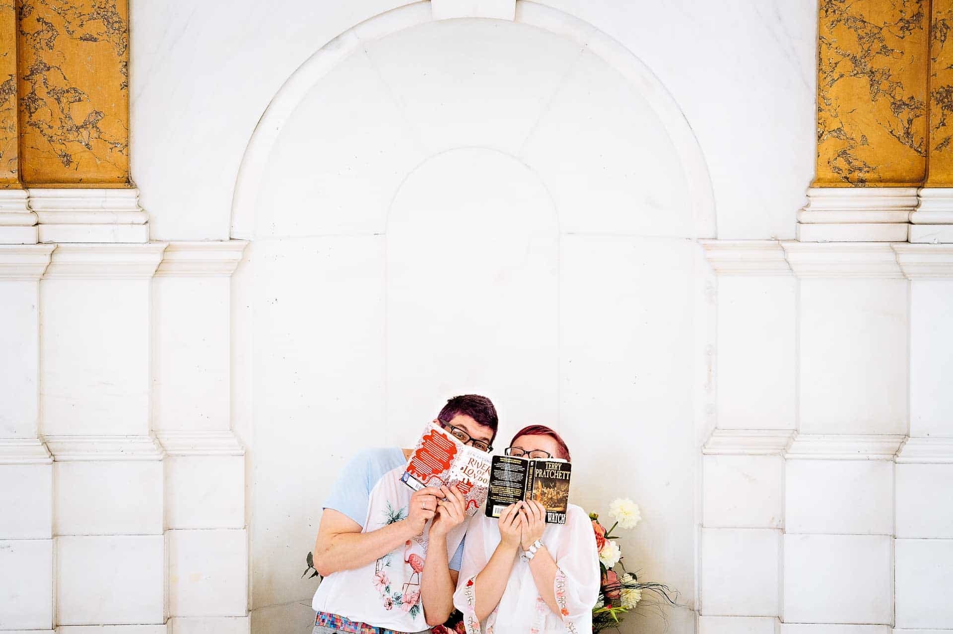 Couple hiding behind books in Camden Town Hall