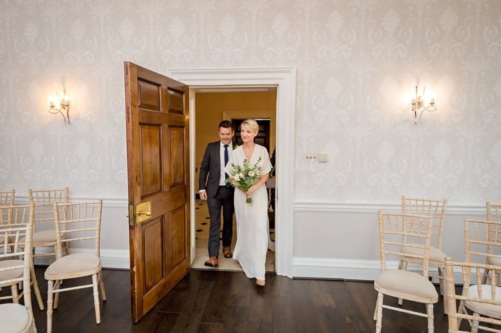 The bride and groom entering the Sheridan Room for their small wedding ceremony at Morden Park House