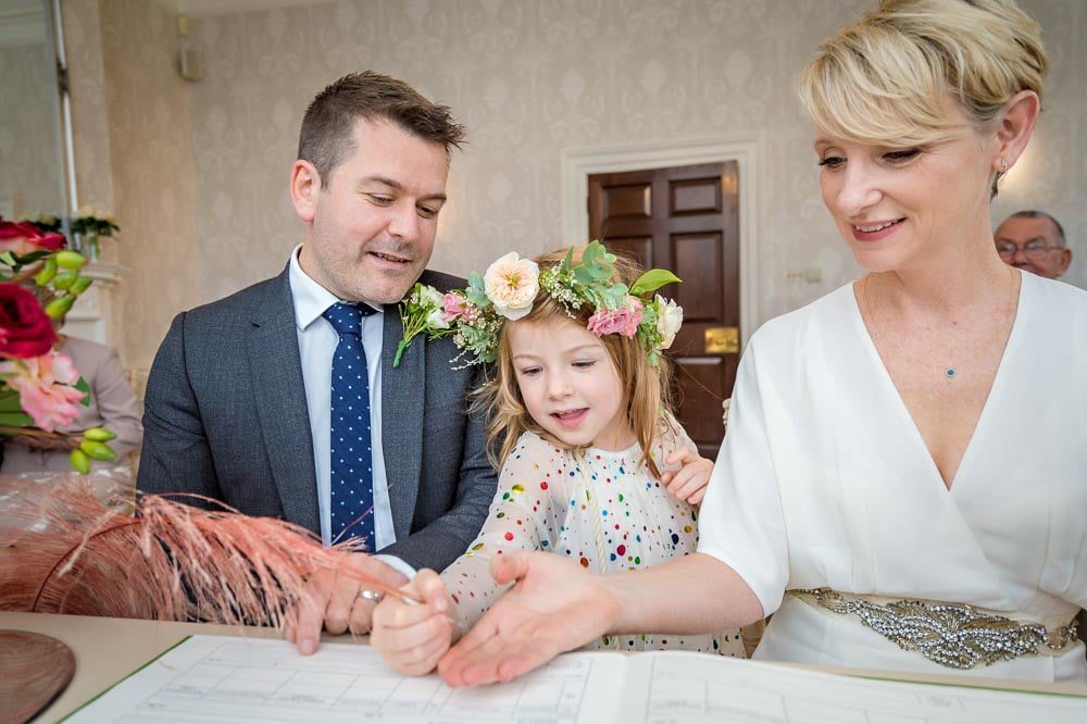 The couple's daughter signs the dummy register with a quill