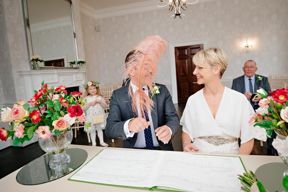 Oversized quill in front of groom's face at dummy register signing