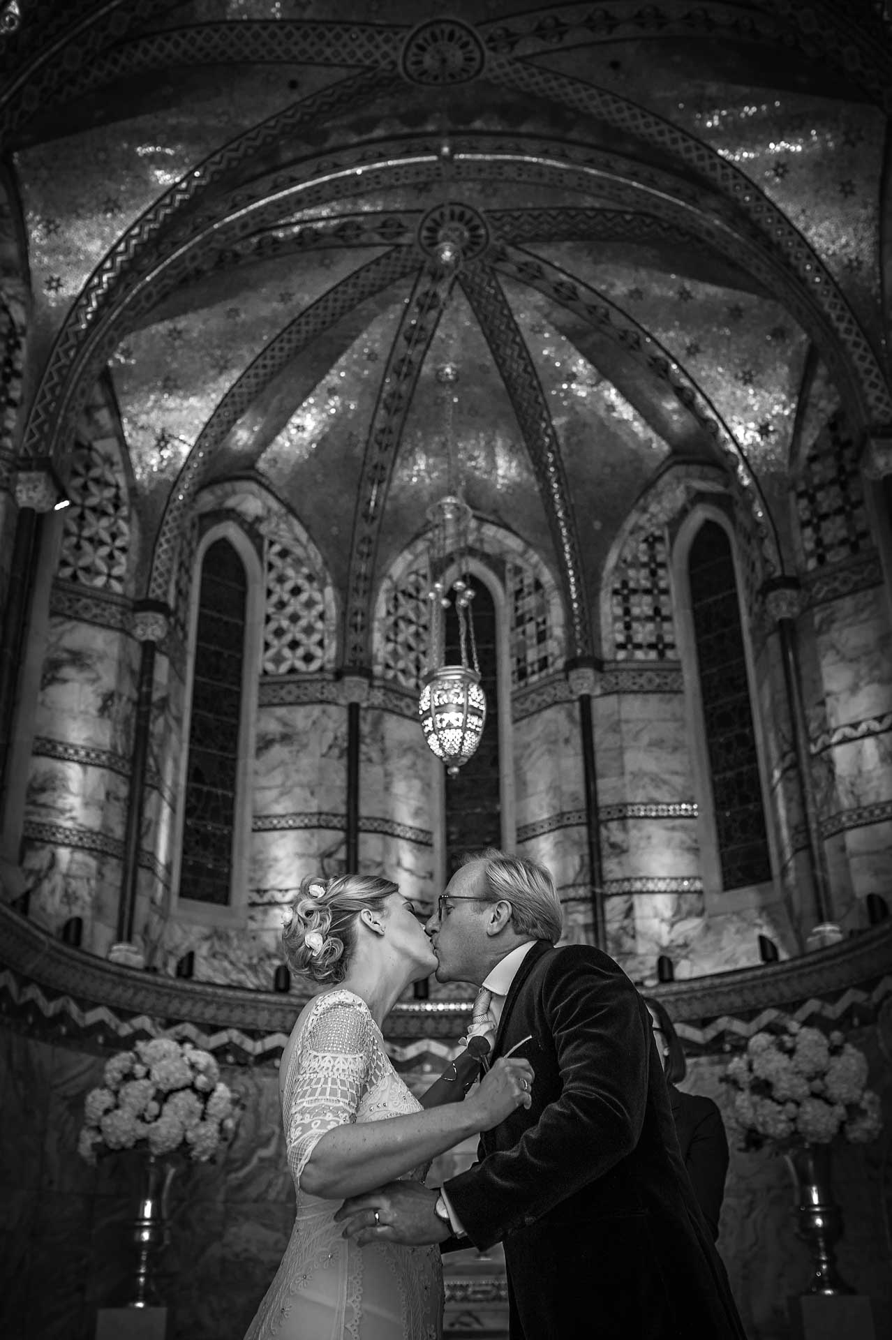 First Kiss at Wedding Showing the Ornate Ceiling of the Fitzrovia Chapel in Balck and White