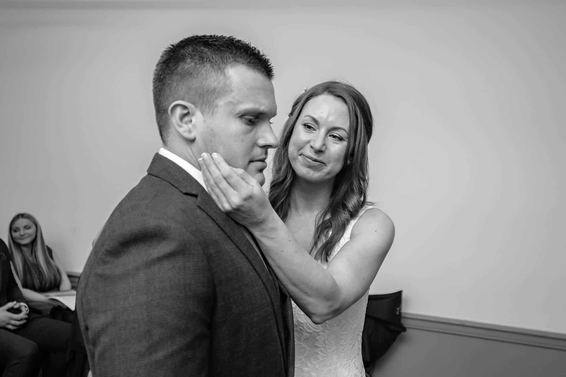 Bride holding serious groom's face during wedding vows.