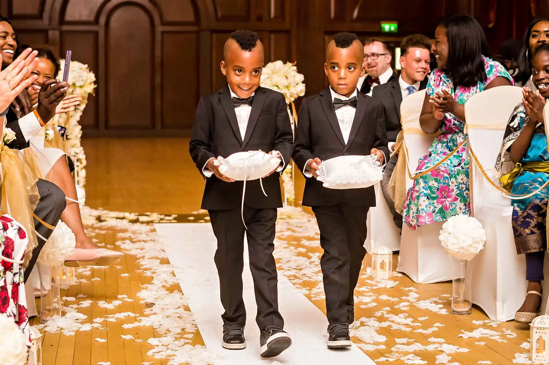 twee pageboys dragen ringen in gangpad in Porchester Hall bruiloft