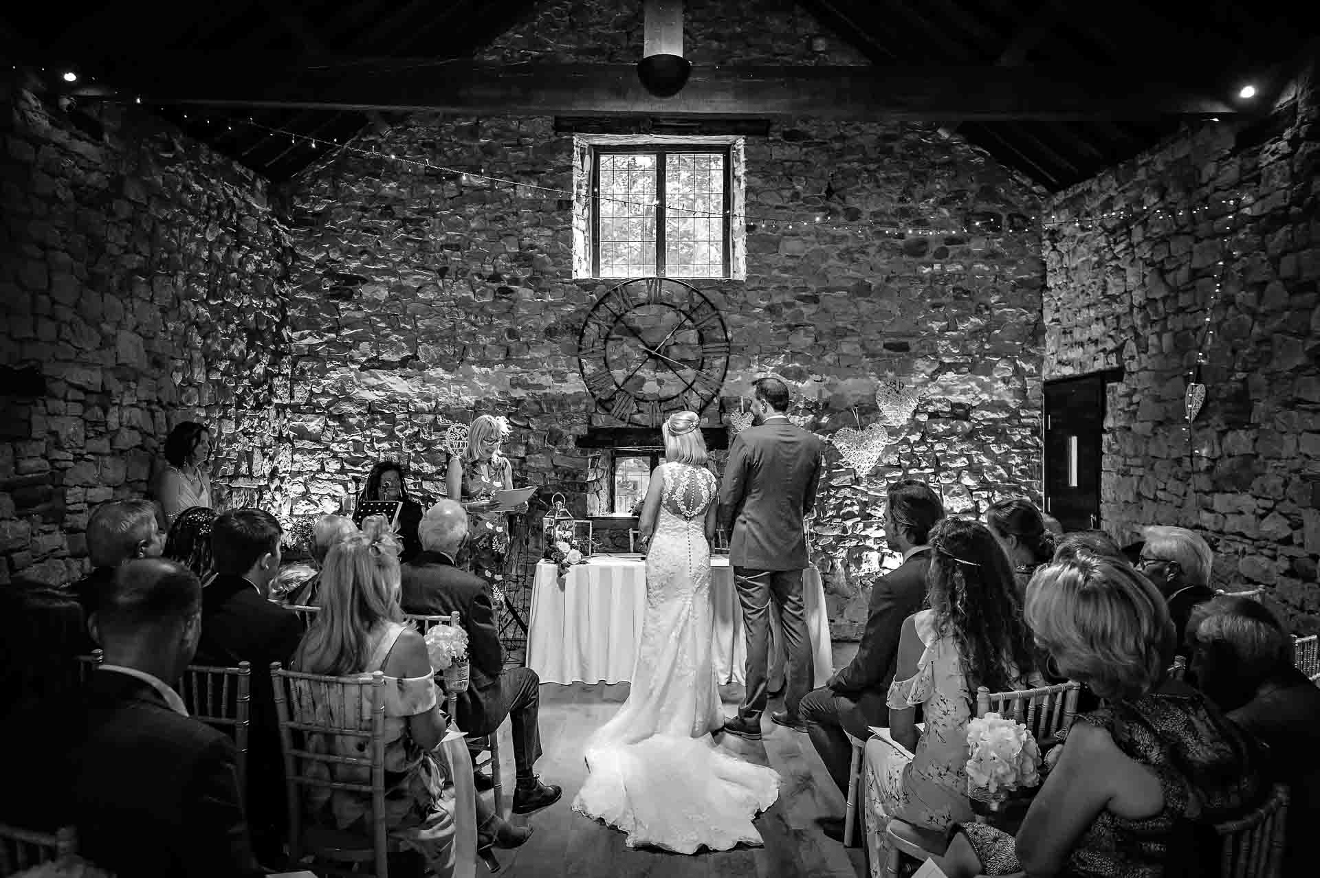 Wide shot of wedding from back as guest gives reading at Pencoed House