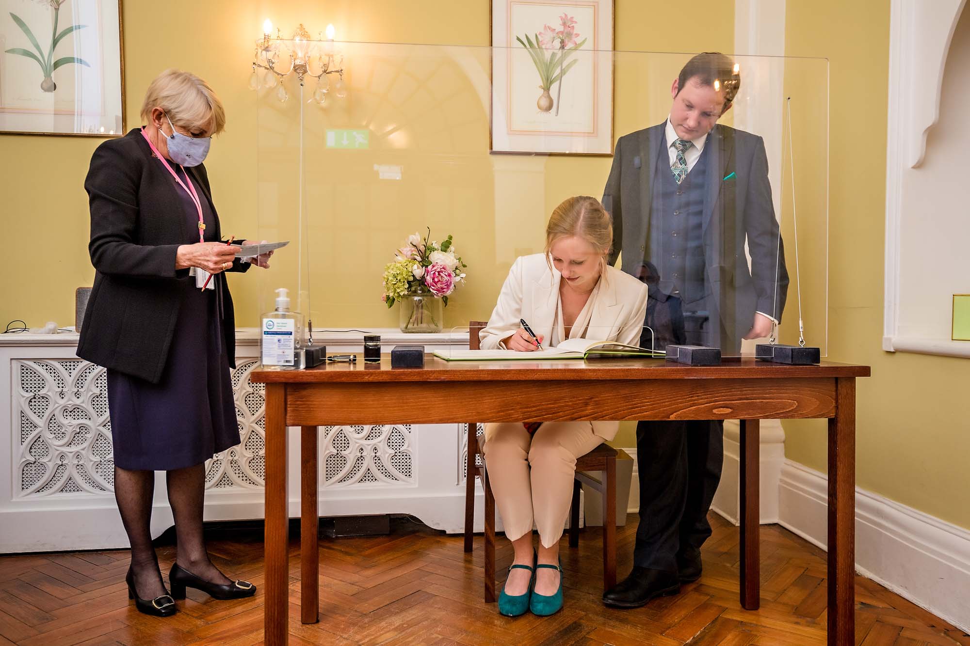 The newly-weds sign the wedding register behind a screen in Chelsea Old Town Hall's Rossetti Room