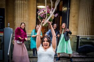 The bride throws the bouquet to four single friends outside Bristol Register Office