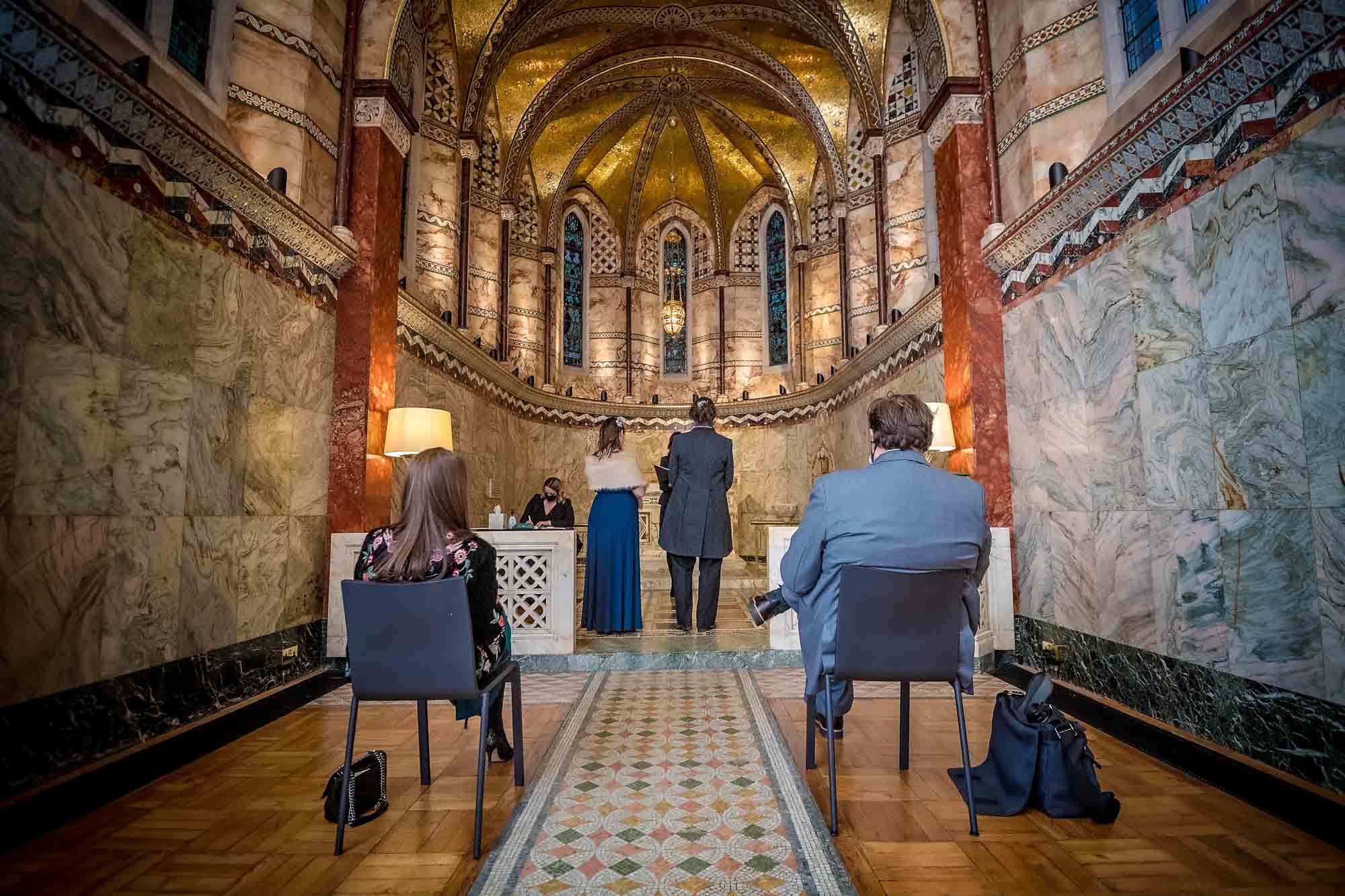 Two seated guests watching the small wedding at Fitzrovia Chapel