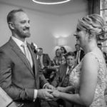 Bearded Groom Smiling at Bride Whilst Placing Ring on her Finger