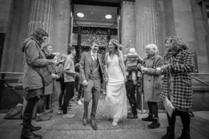 Bride and groom laughing in shower of confetti outside Bristol Register Office