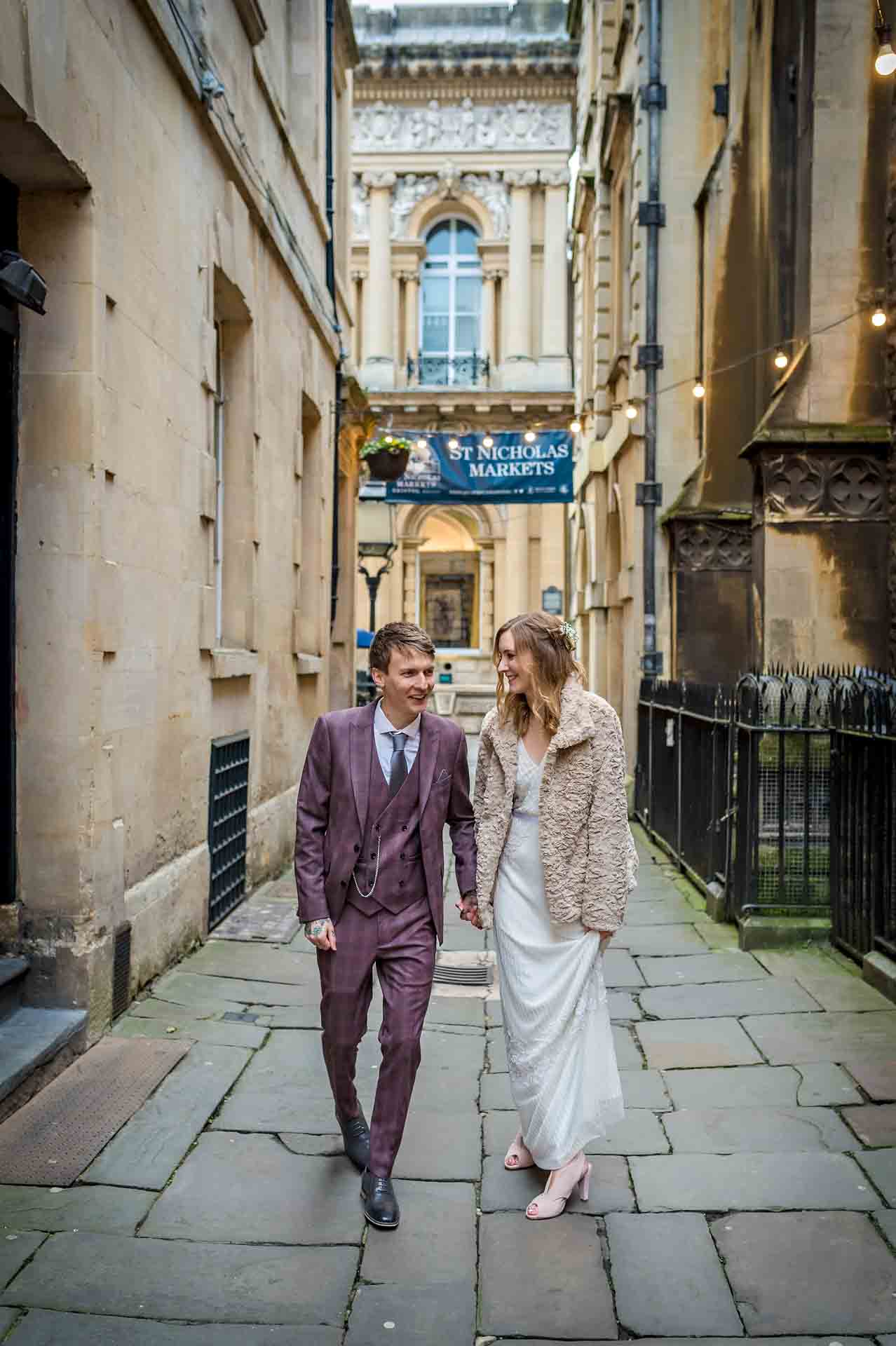Bride and groom walking down narrow street in Bristol