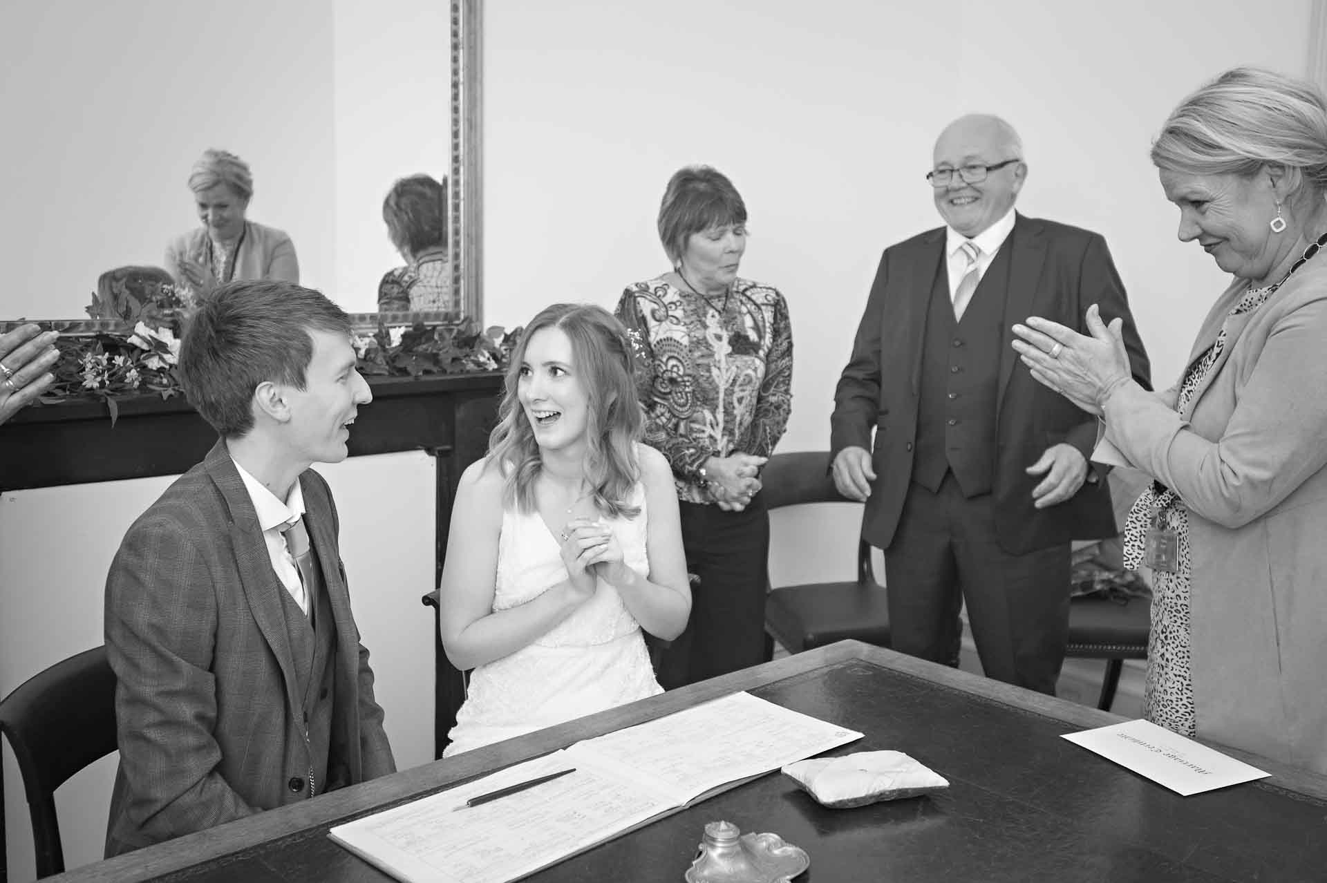 Newly-weds chatting whilst being applauded after wedding register signing in Bristol