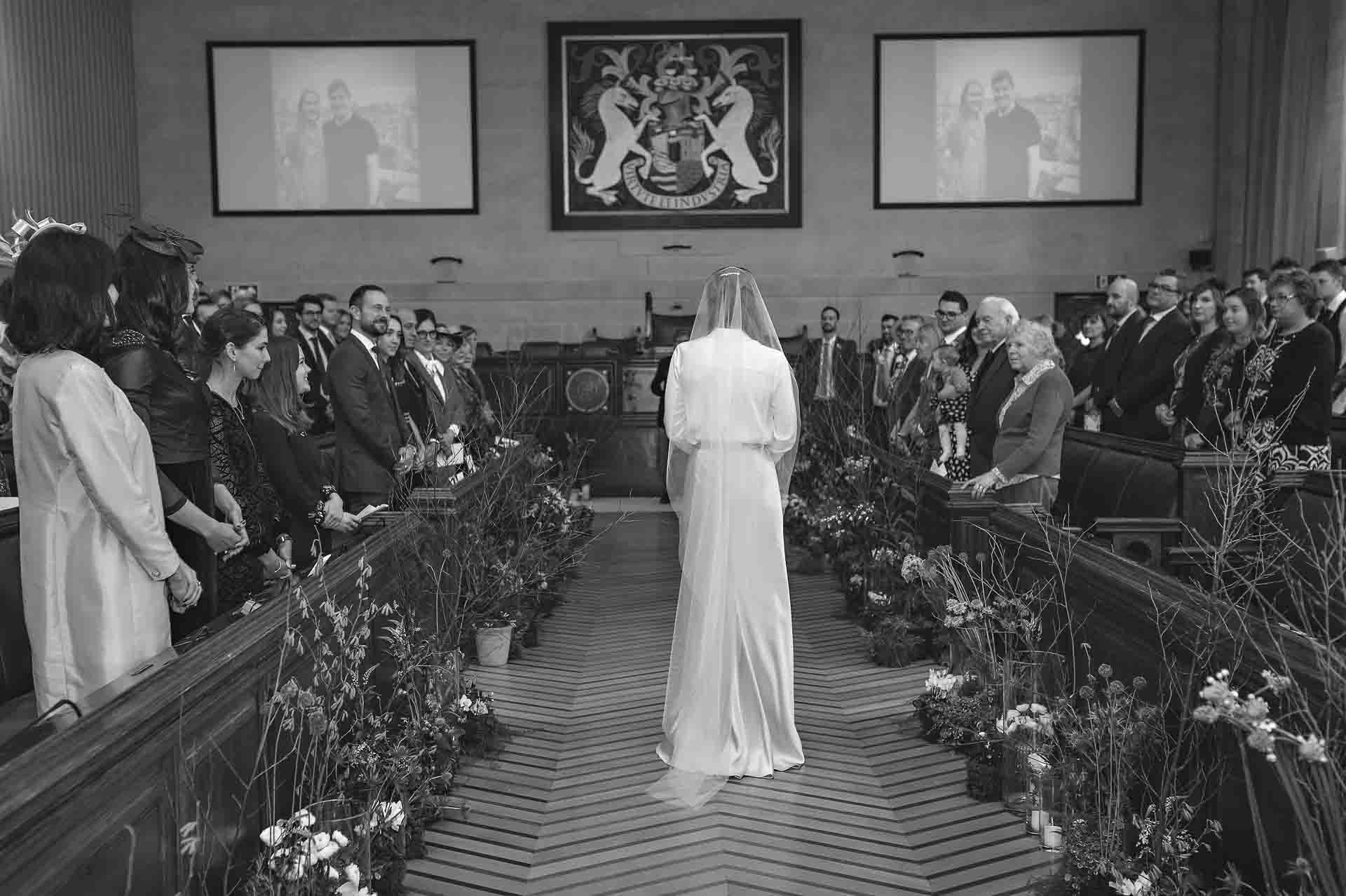 The bride walks down the aisle of the Council Chamber at Bristol City Hall