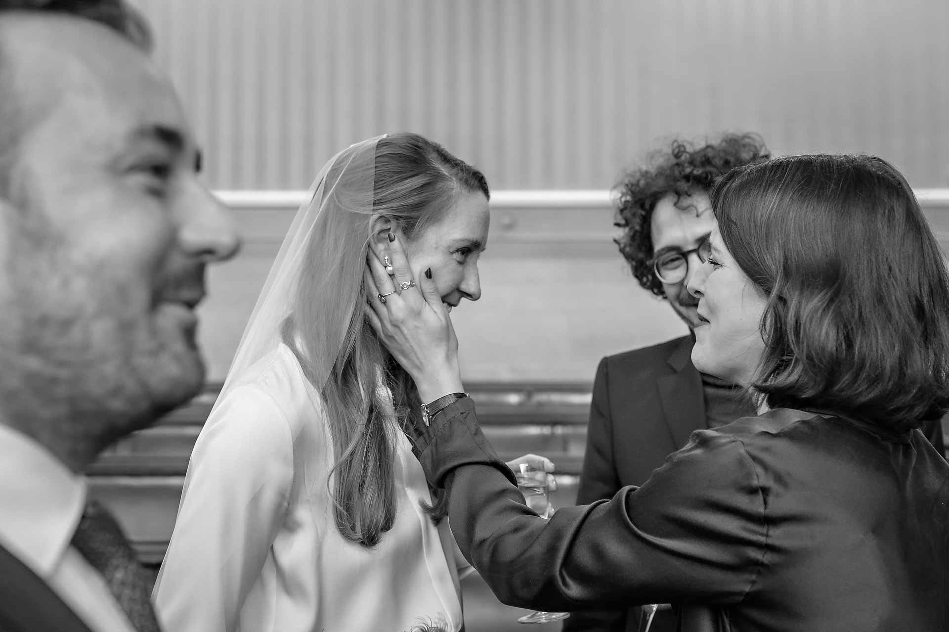 A guest touches the cheek of the bride at a wedding in Bristol City Hall