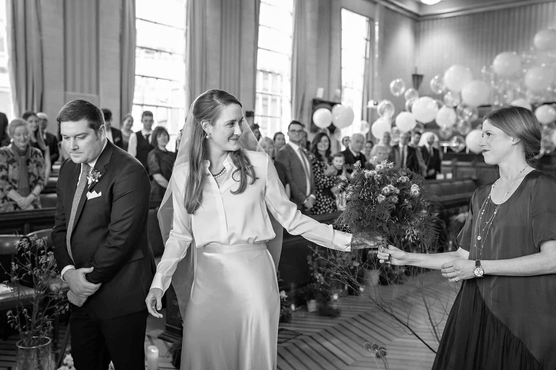 Bride hands bouquet to bridesmaid at Bristol City Hall wedding
