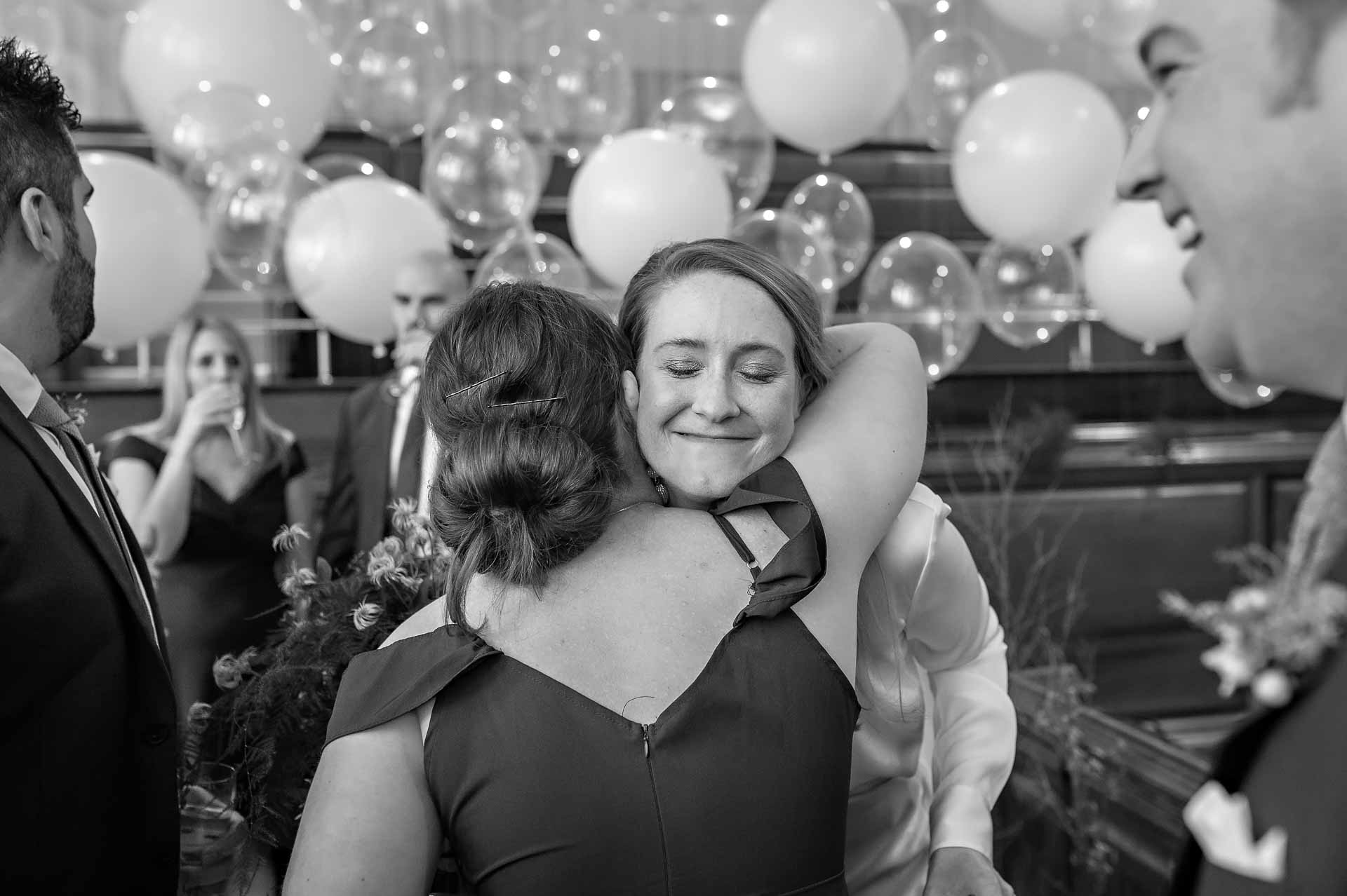Bride looking happy as she is hugged by guest at Bristol wedding
