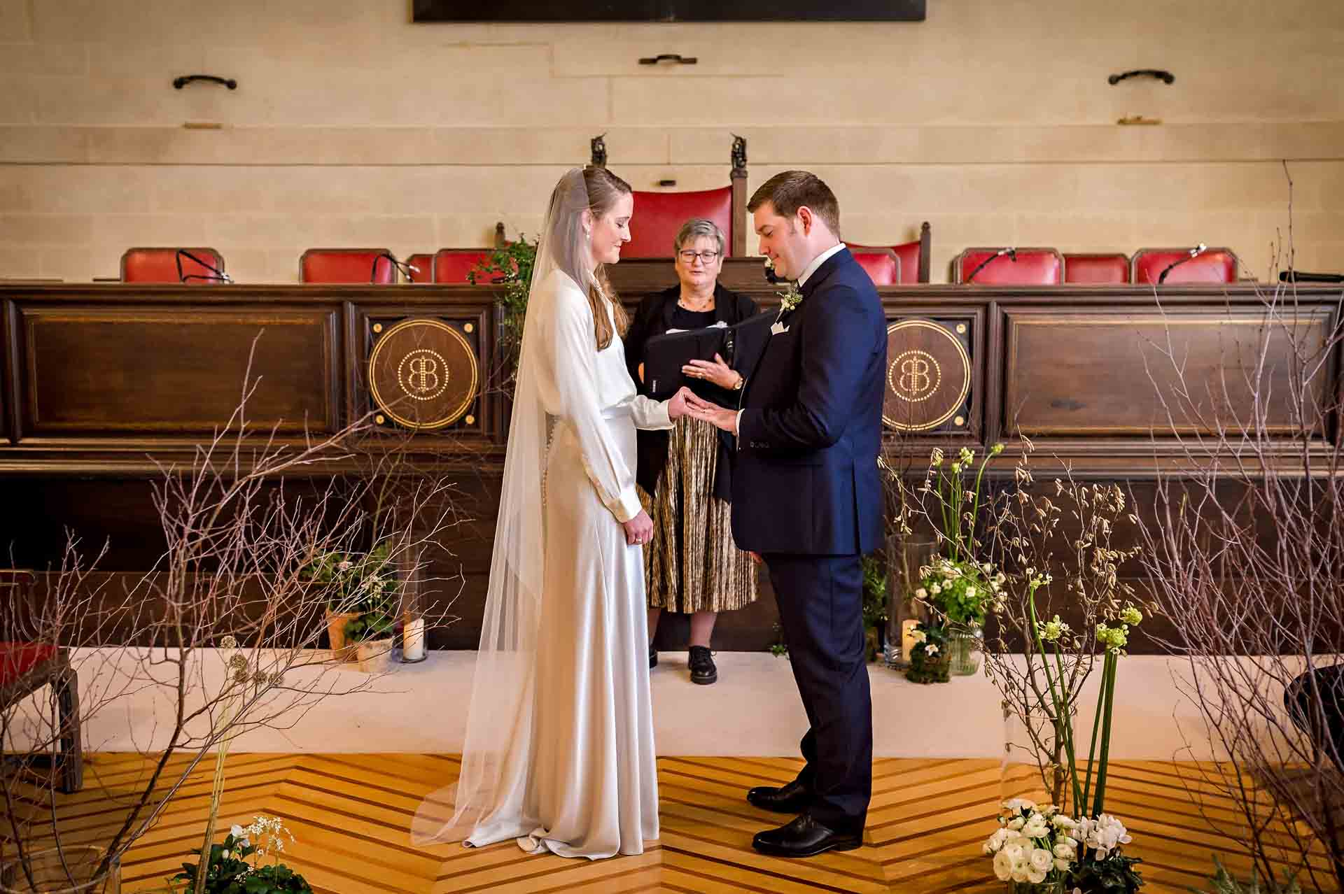 The bride places the ring on the groom's finger at Bristol City Hall