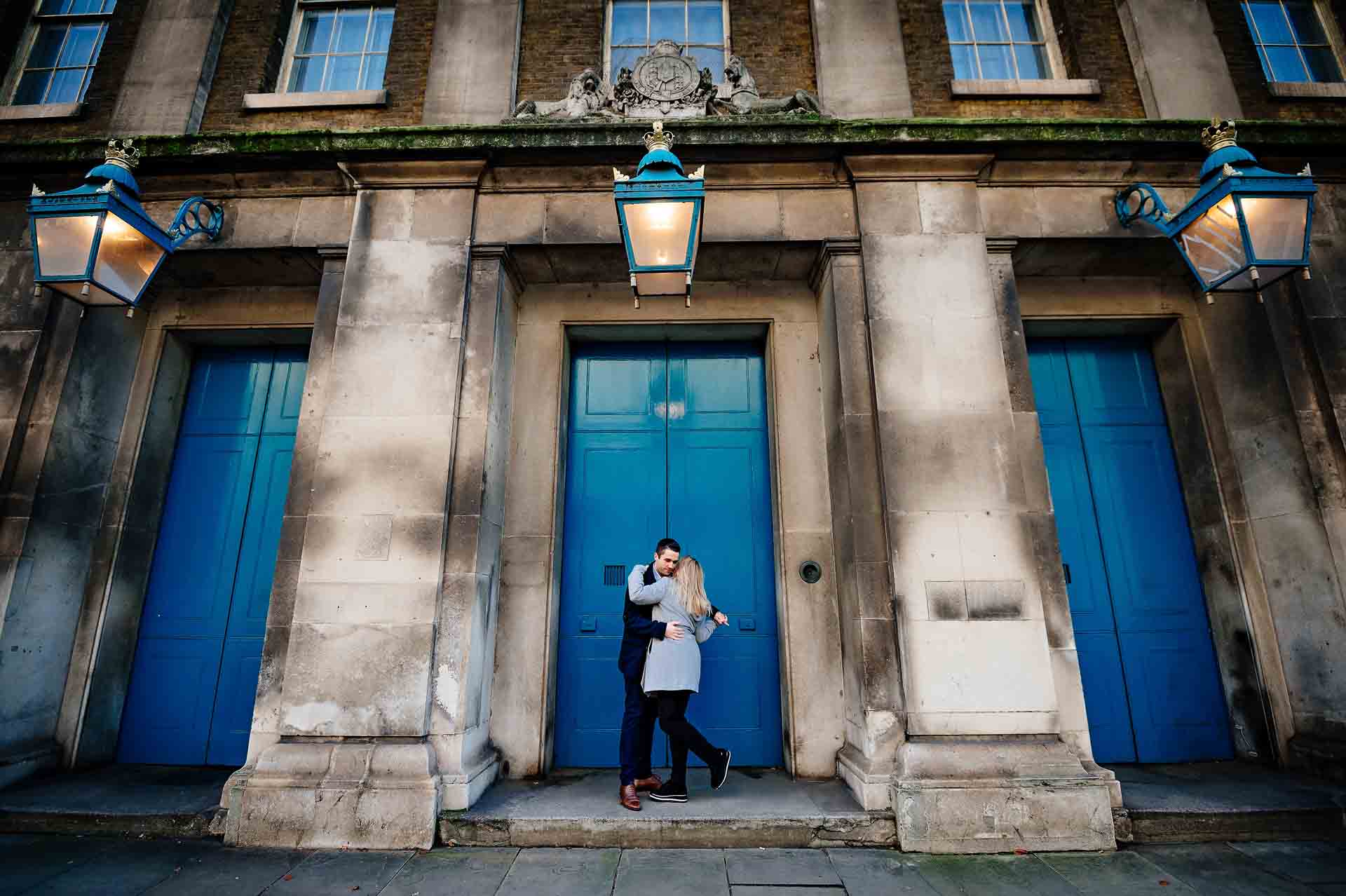 Couple hugging in middle blue doorway of three in London for their engagement photography