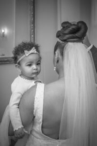 A baby looking over the bride&#039;s shoulder at a wedding ceremony