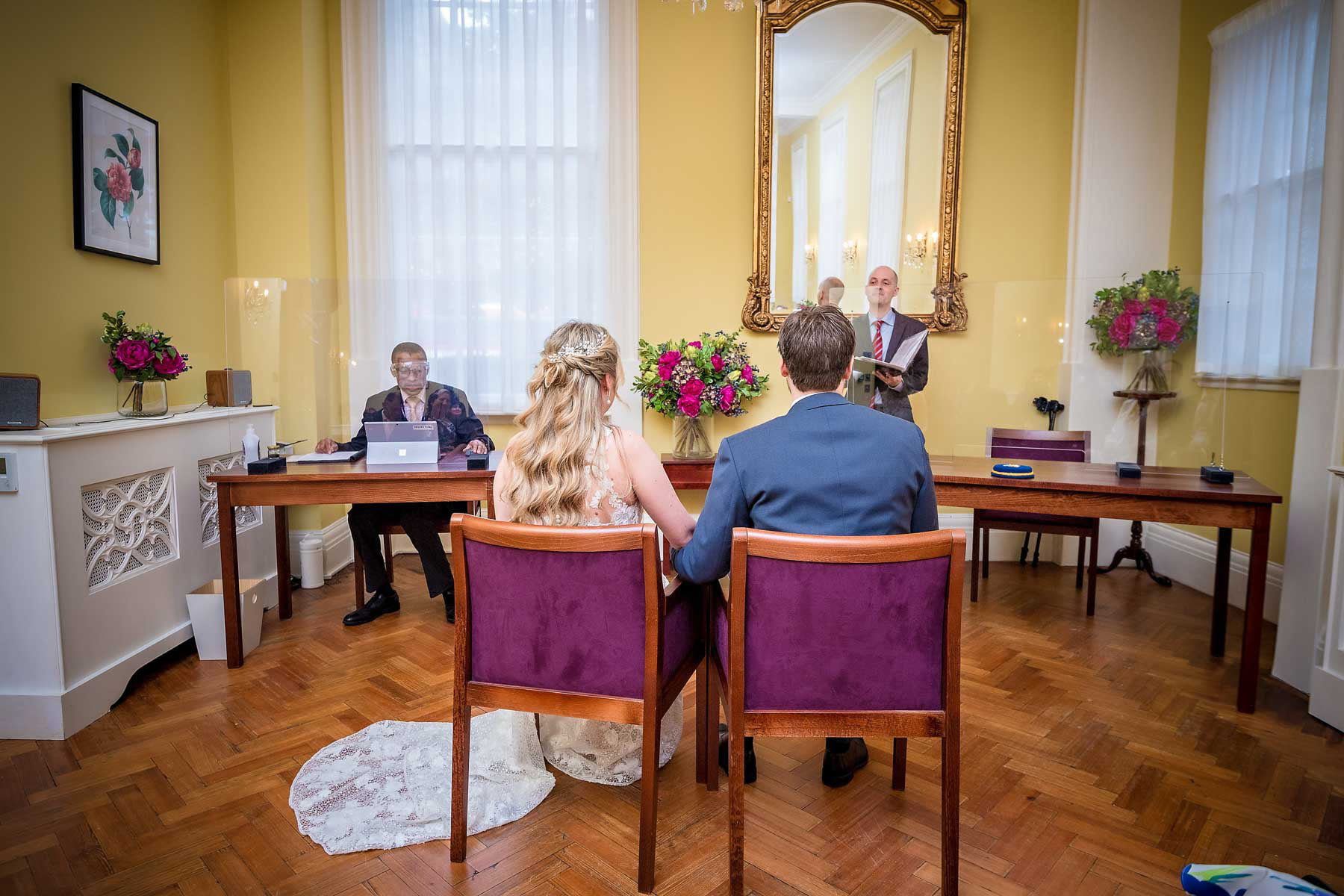 The bride and groom photographed seated from the back in the Brydon Room, Chelsea