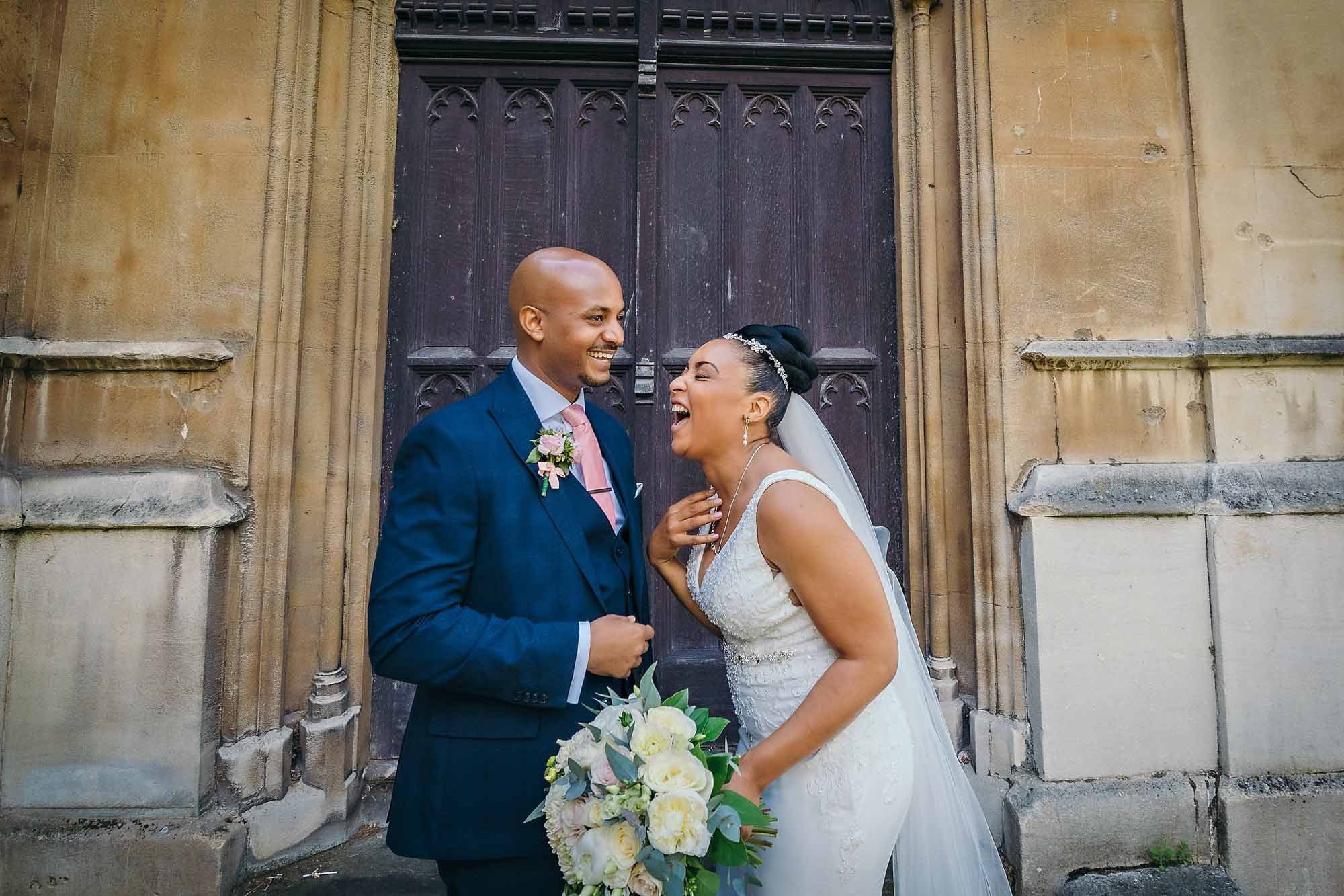 Bride and groom laughing together outside St Luke's Church in Chelsea, London