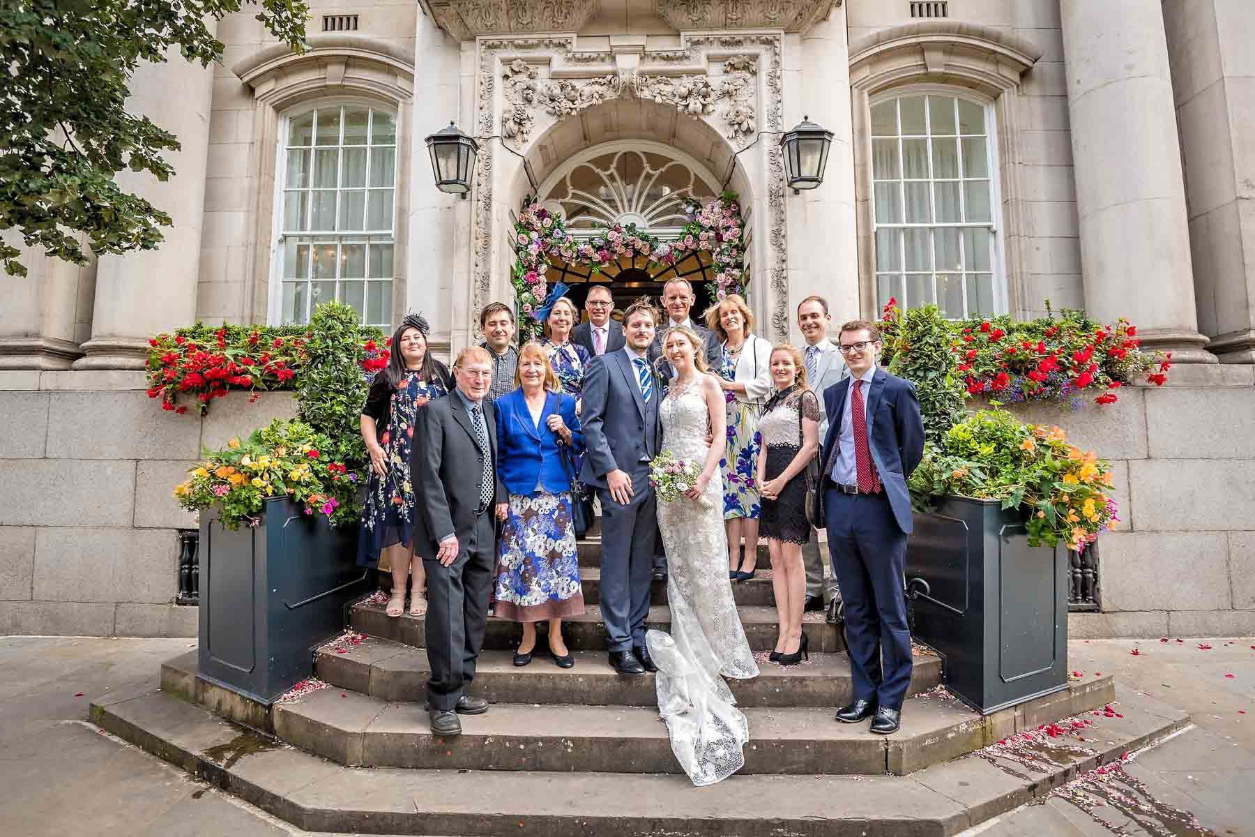 Newlyweds with close friends and family posing on steps of Chelsea Register Office