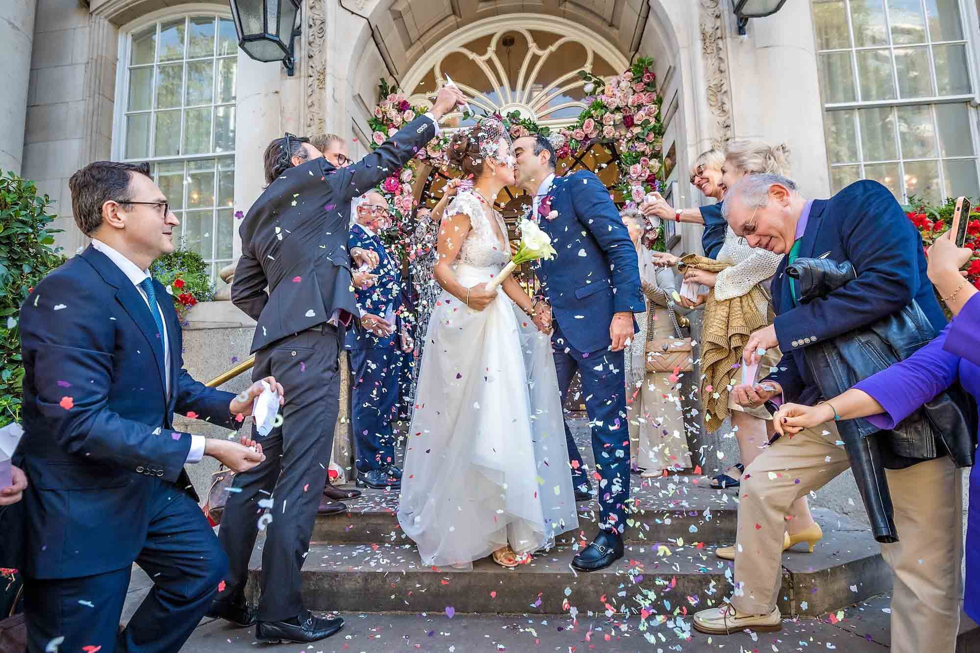 The couple kiss whilst being showered in cofetti on the steps outside Chelsea Old Town Hall