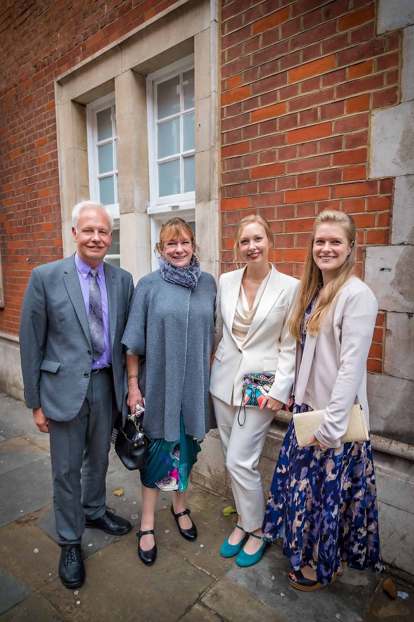 Wedding couple posing with family on street at side door of Chelsea Old Town Hall