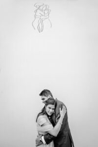 Black and white portrait of wedding couple recreating wall art of a couple hugging above them