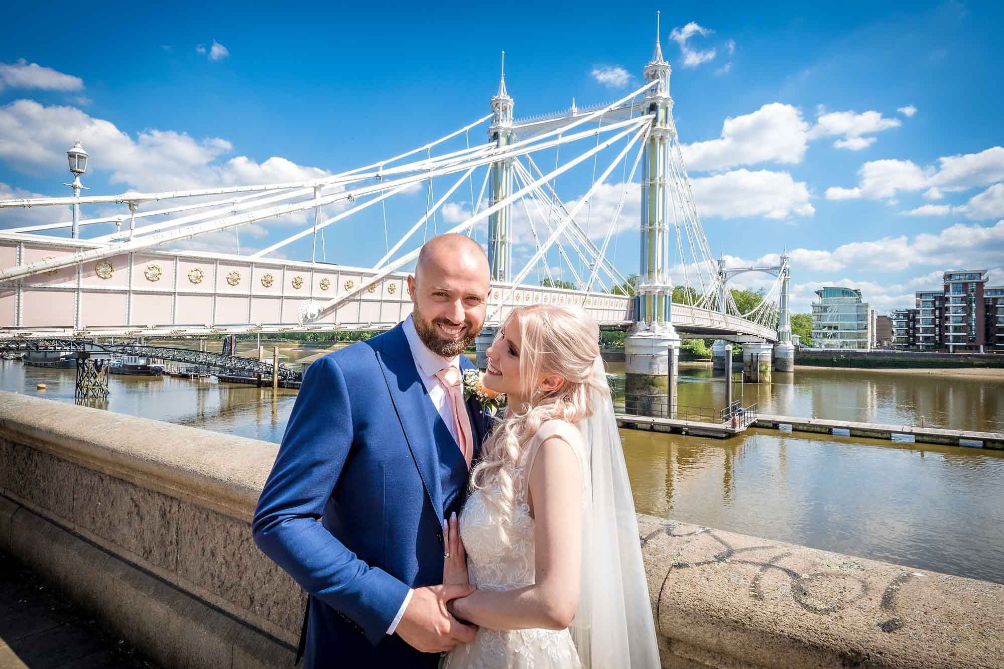 A bride looks at her groom with the Albert Bridge in London in the background