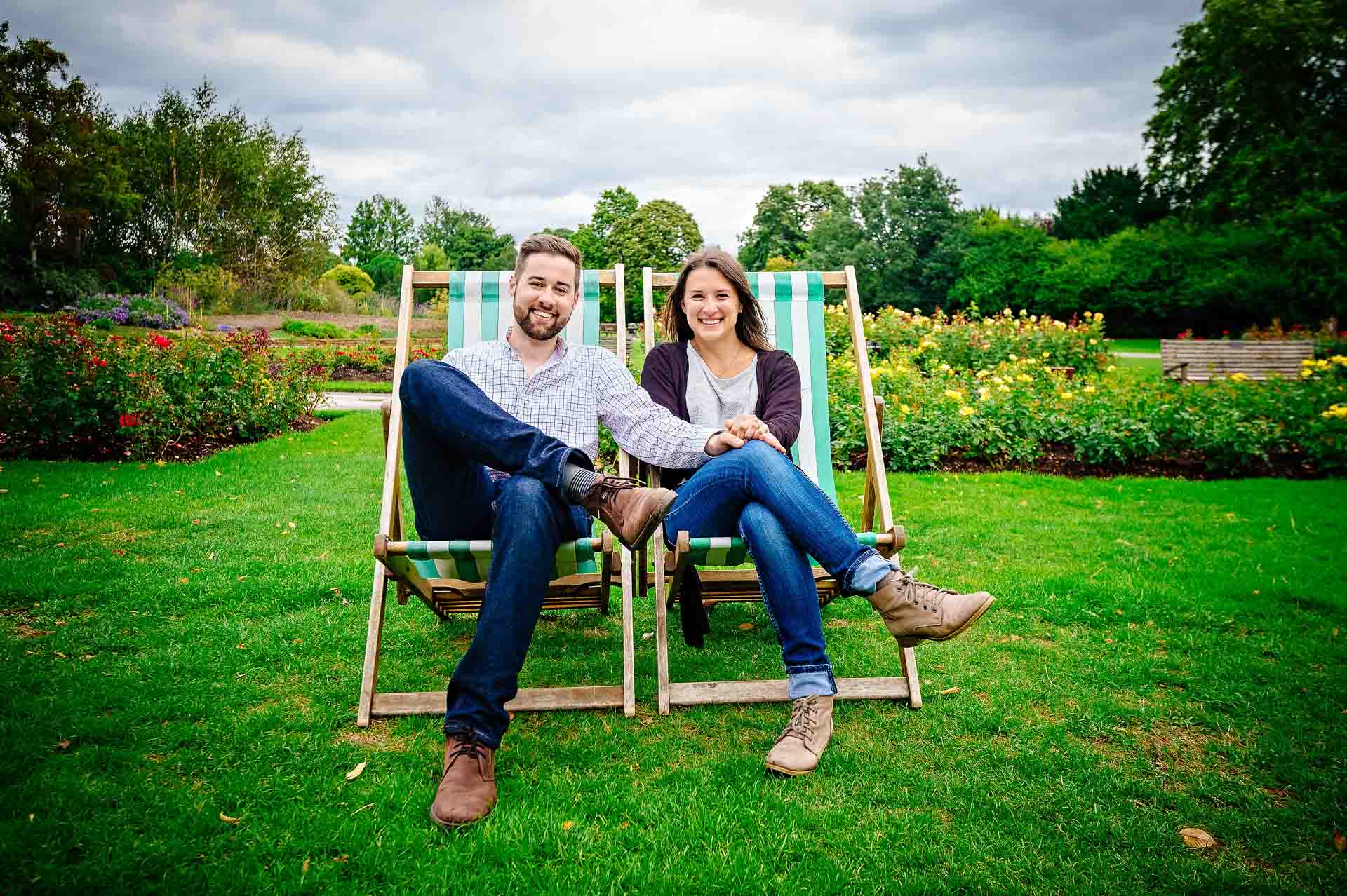 Smiling couple sitting in deck chairs in London park