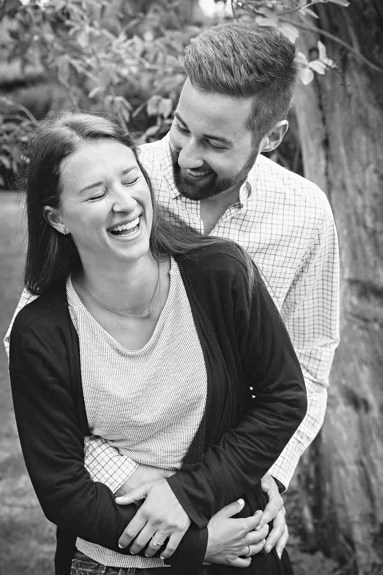 Black and white photo of engaged couple laughing together