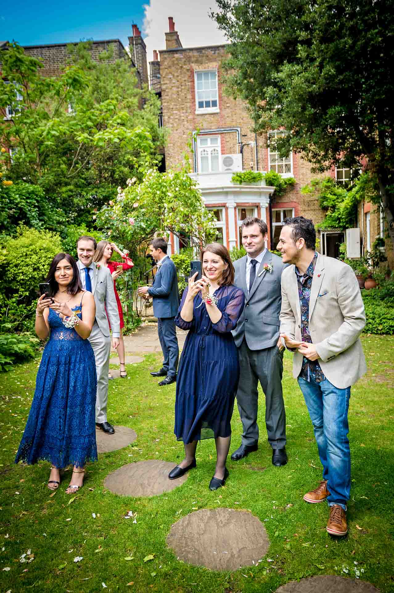 Guests taking photos in garden at wedding in Southwark Registry Office