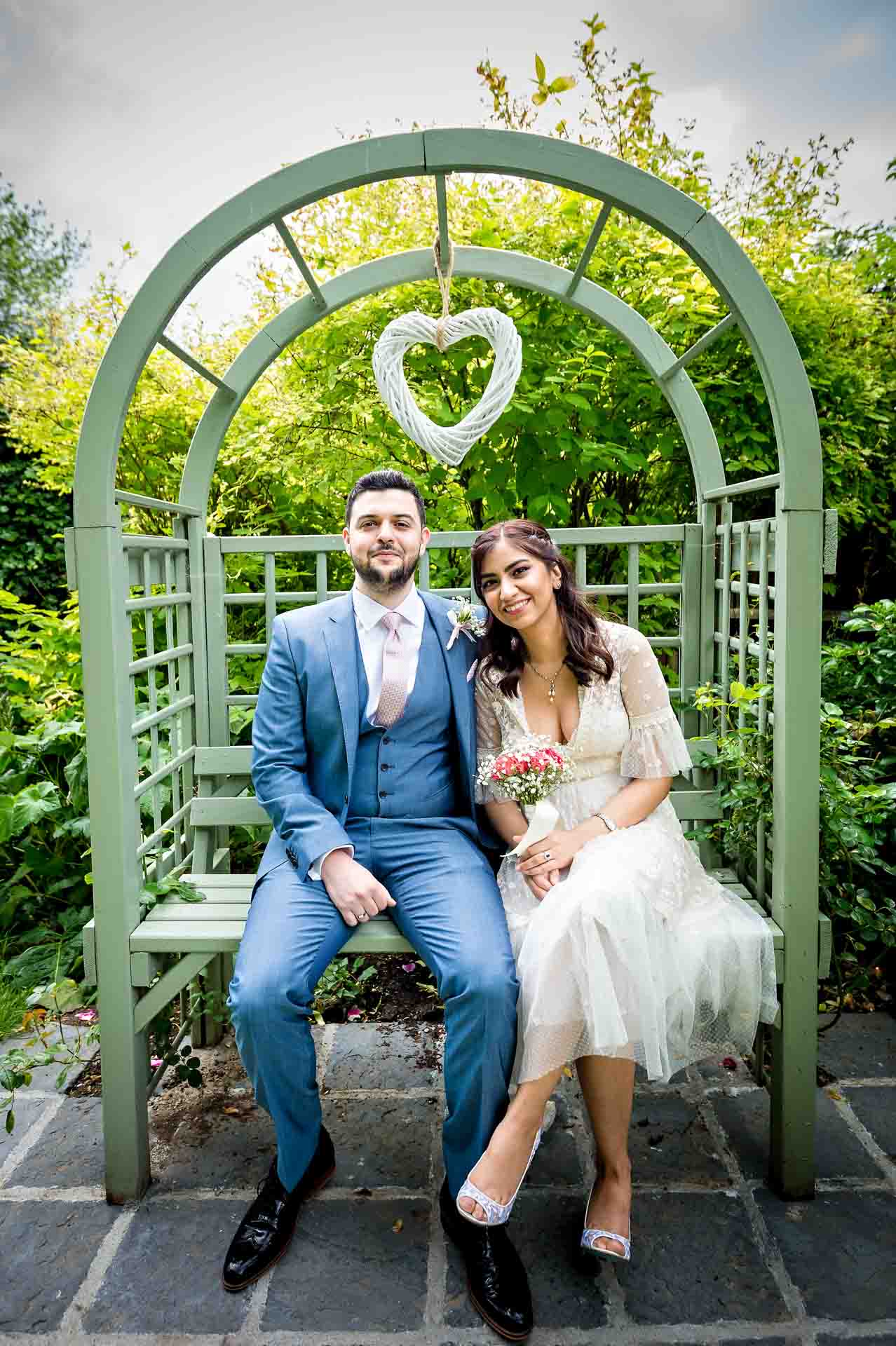 Couple sitting in garden seat under heart at Southwark Register Office