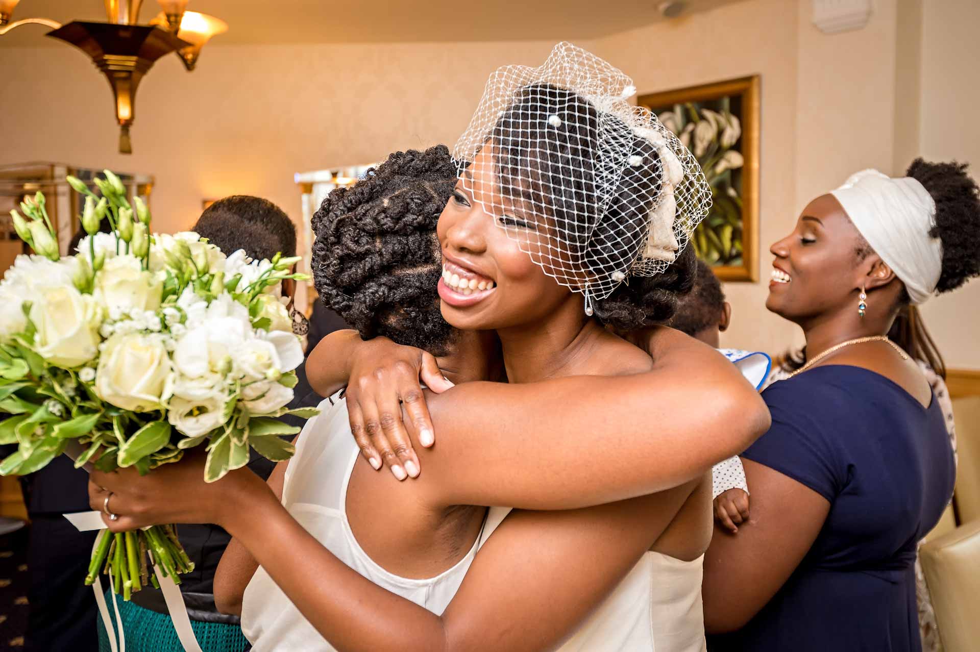 Bride holding bouquet and hugging family member after wedding