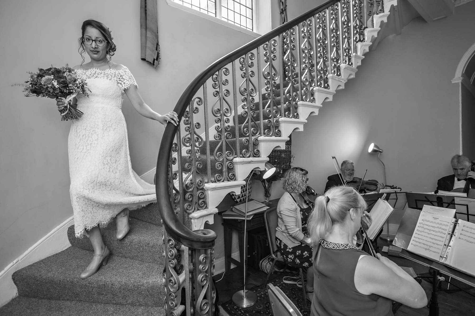 Bride descending downstairs at wedding with string quartet playing