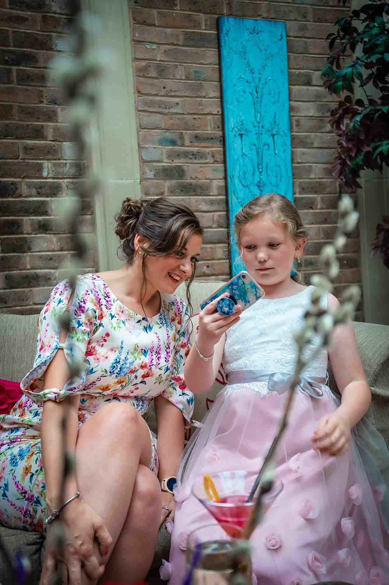 Bridesmaid and female guest looking at phone