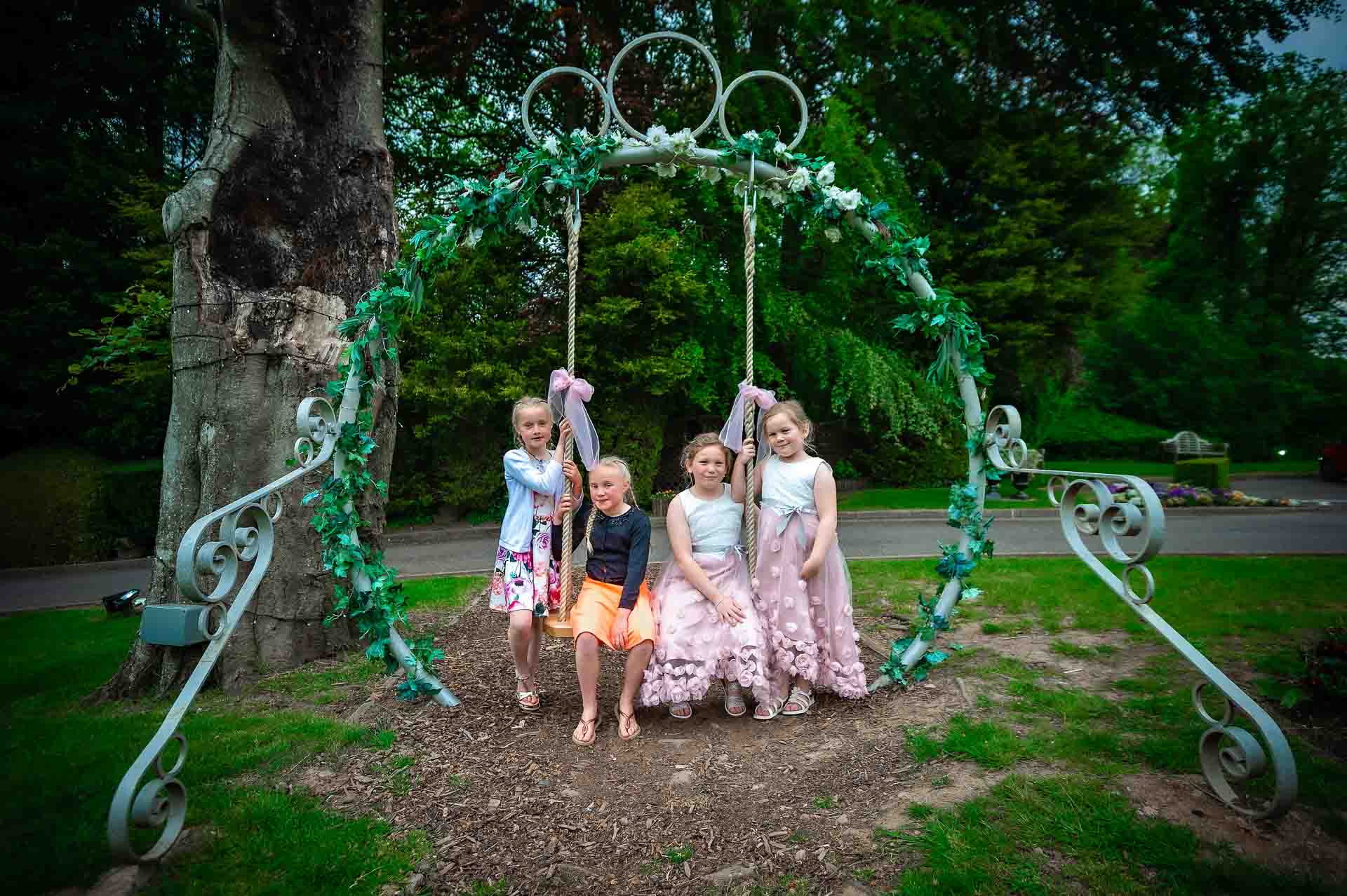 4 girls on decorative swing at wedding