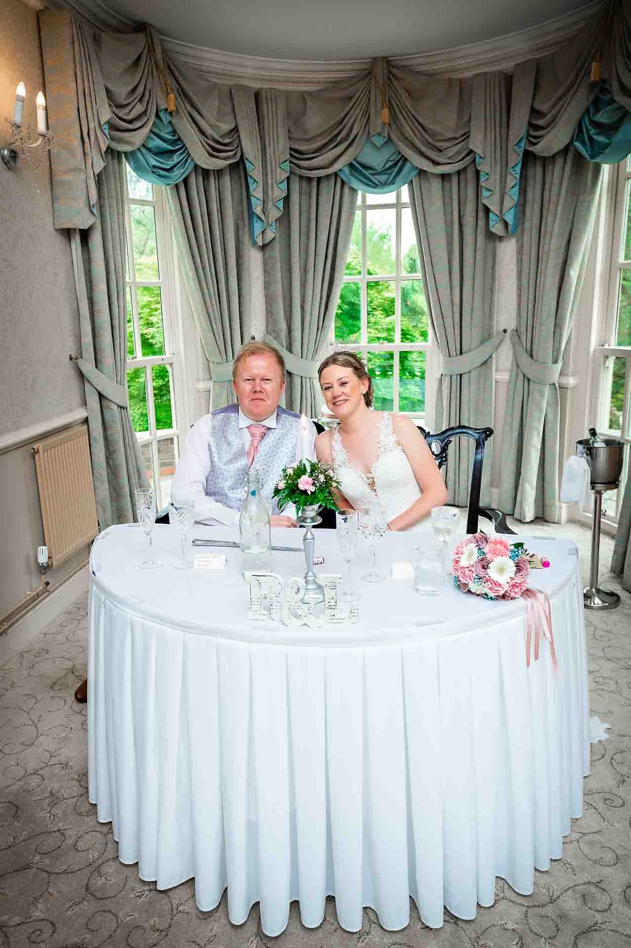 Bride and Groom sitting at wedding breakfast on their own table in De Courceys Manor