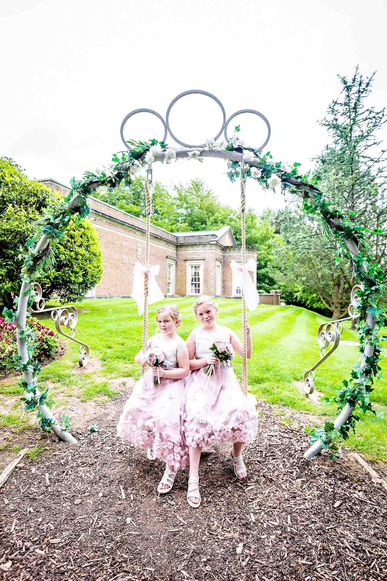 Two bridesmaids on decorative swing at wedding