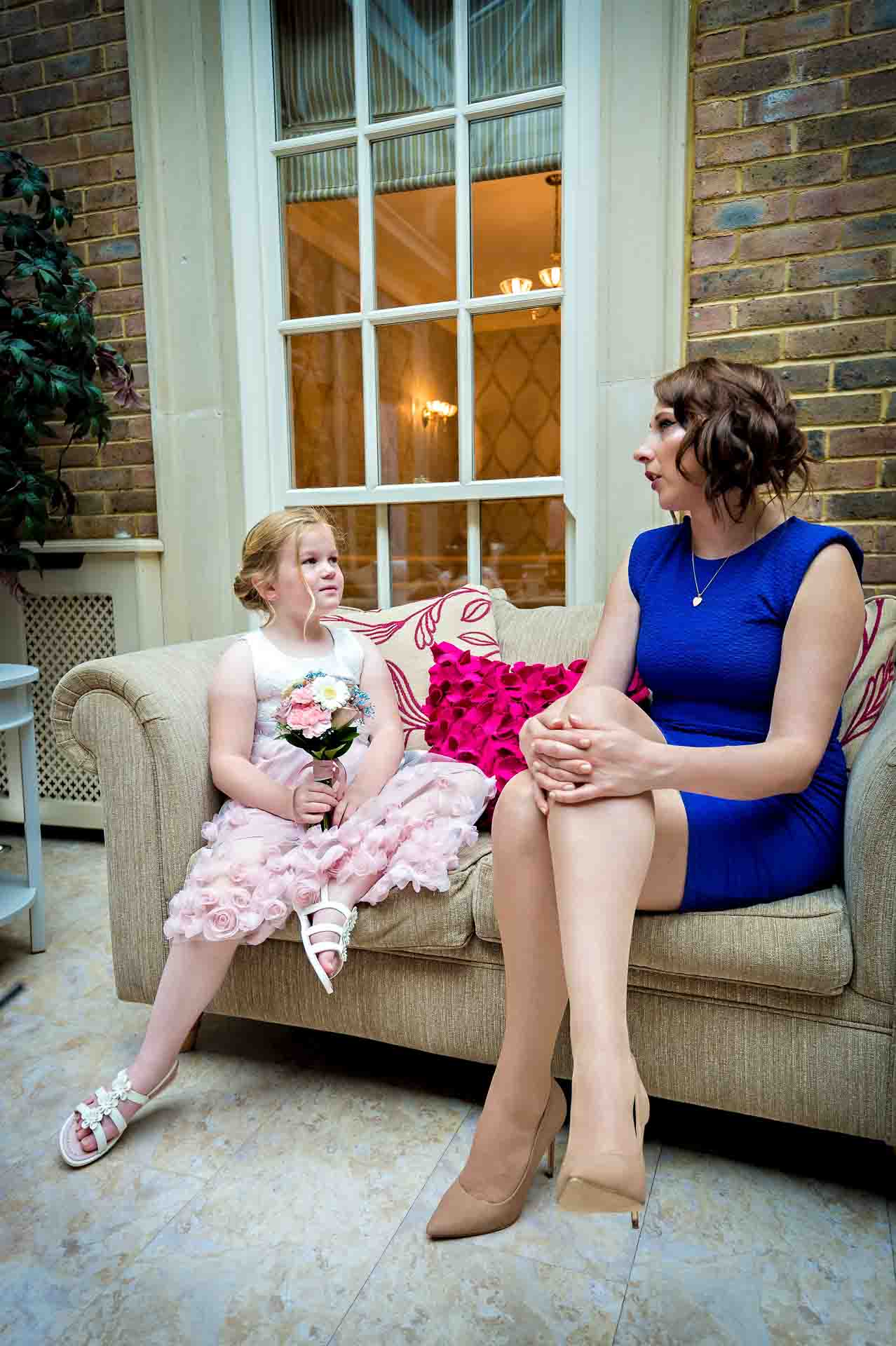 Bridesmaid chatting with female guest in blue dress at wedding