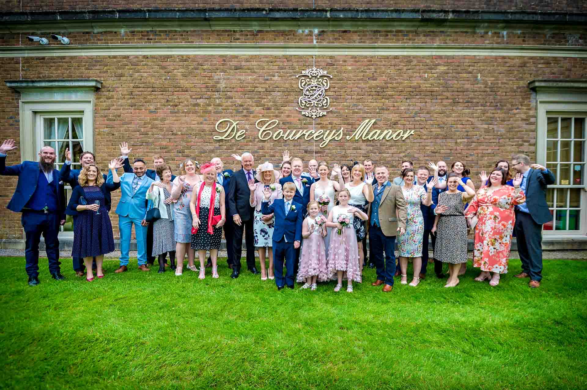 Photo of whole wedding party taken with DeCourceys Manor logo on wall behind