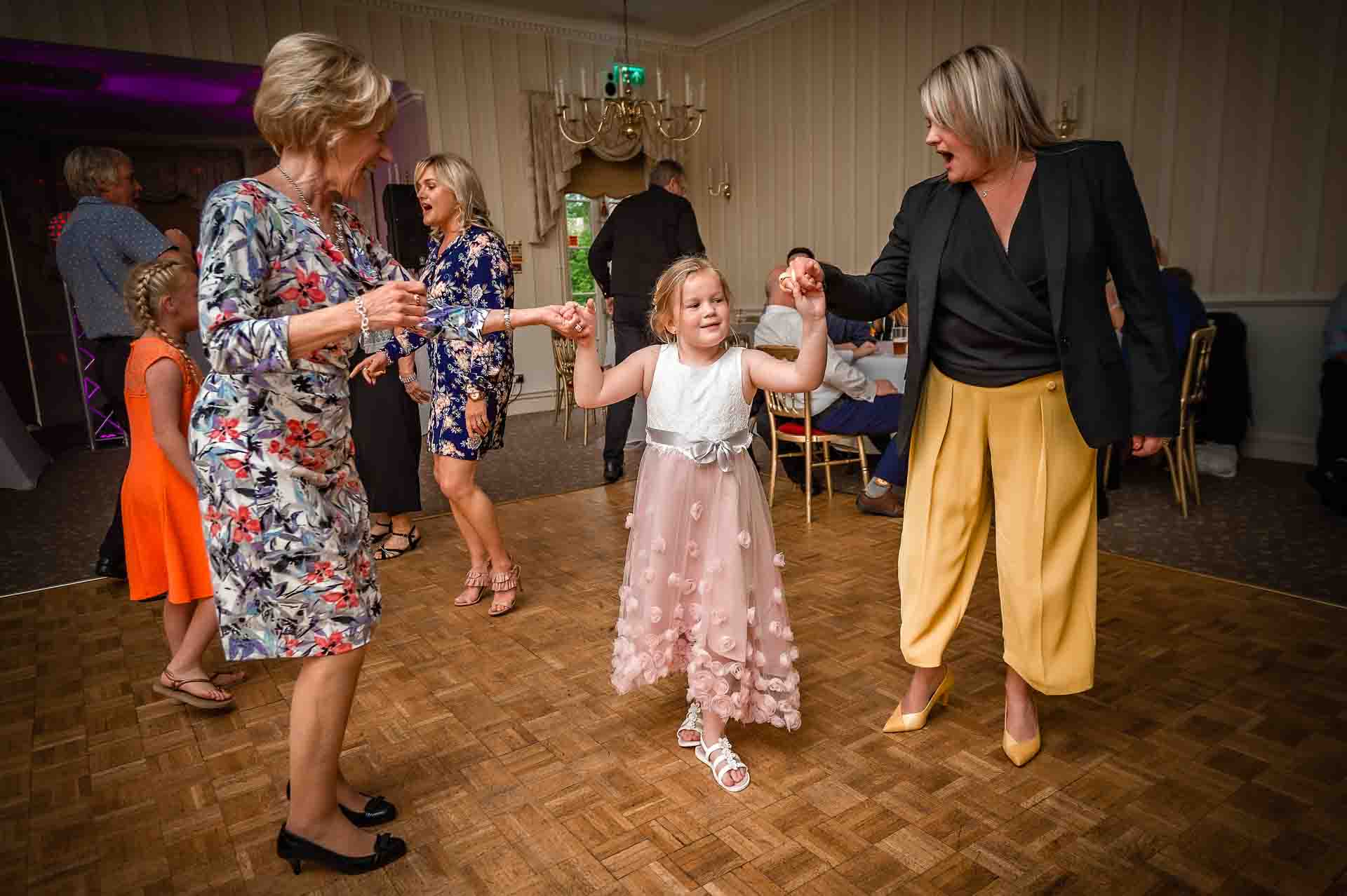 Two women dancing with girl at wedding