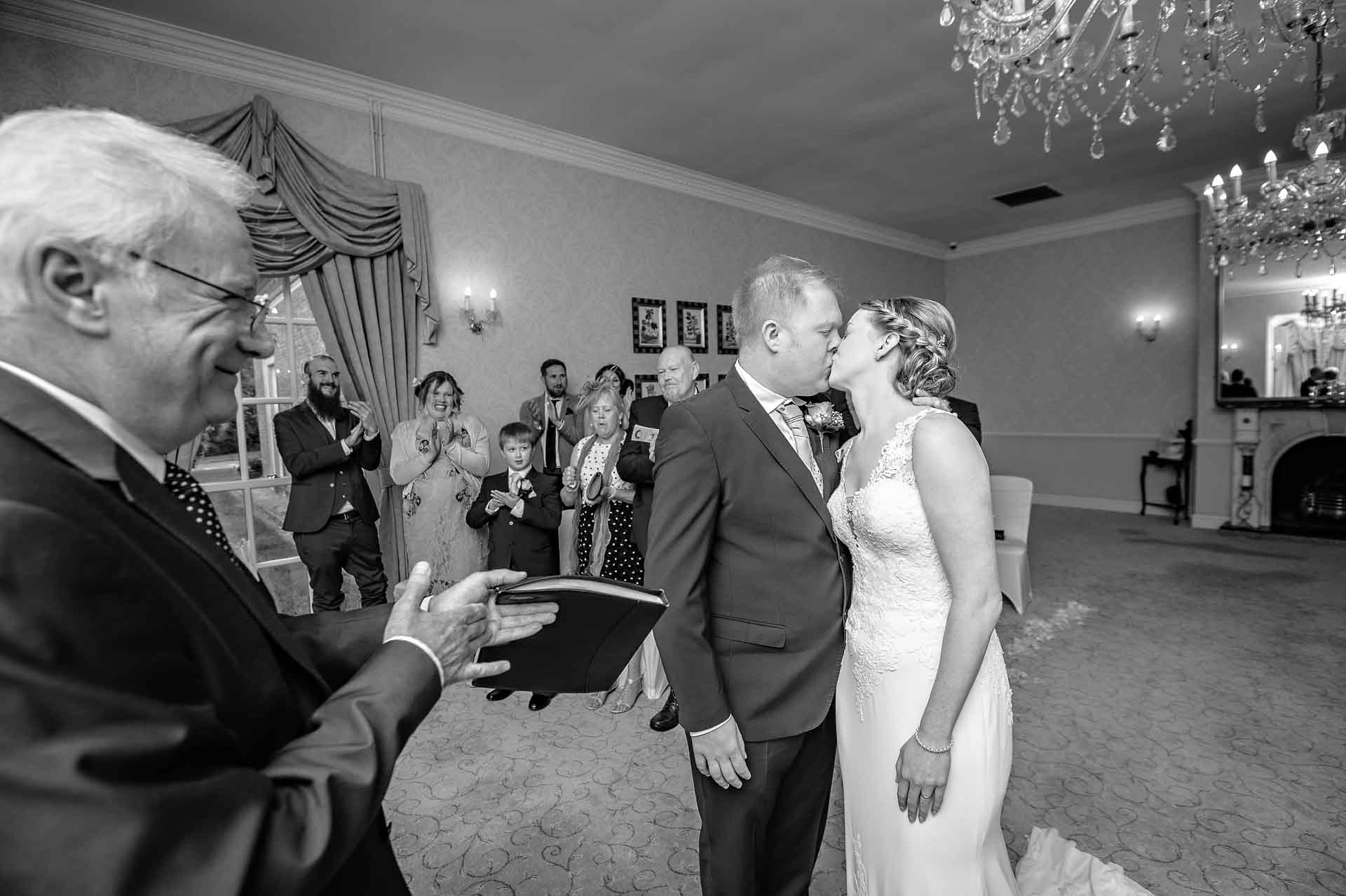 First Kiss at wedding with registrar clapping