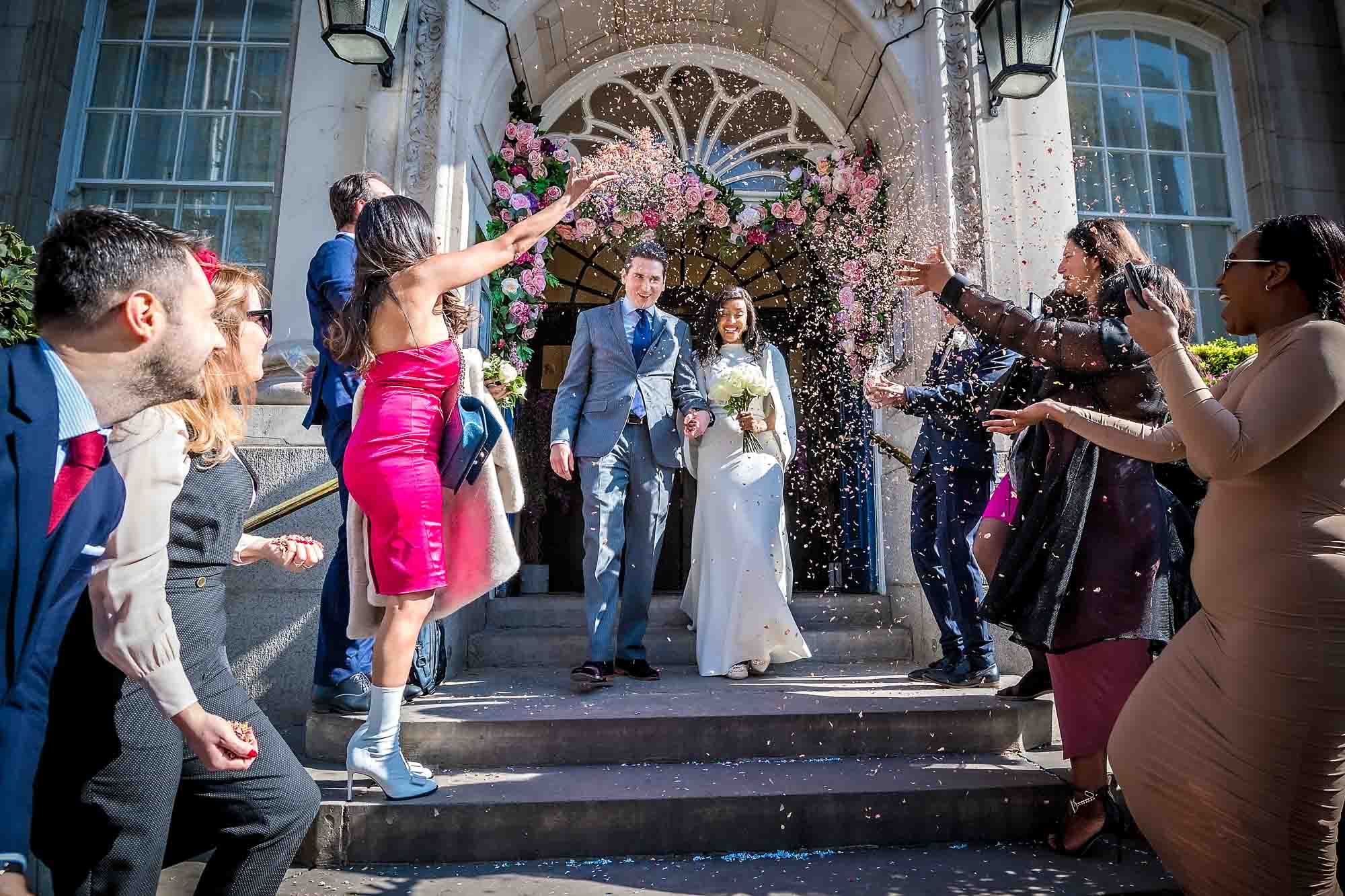 The couple are showered by confetti at their Chelsea Old Town Hall wedding