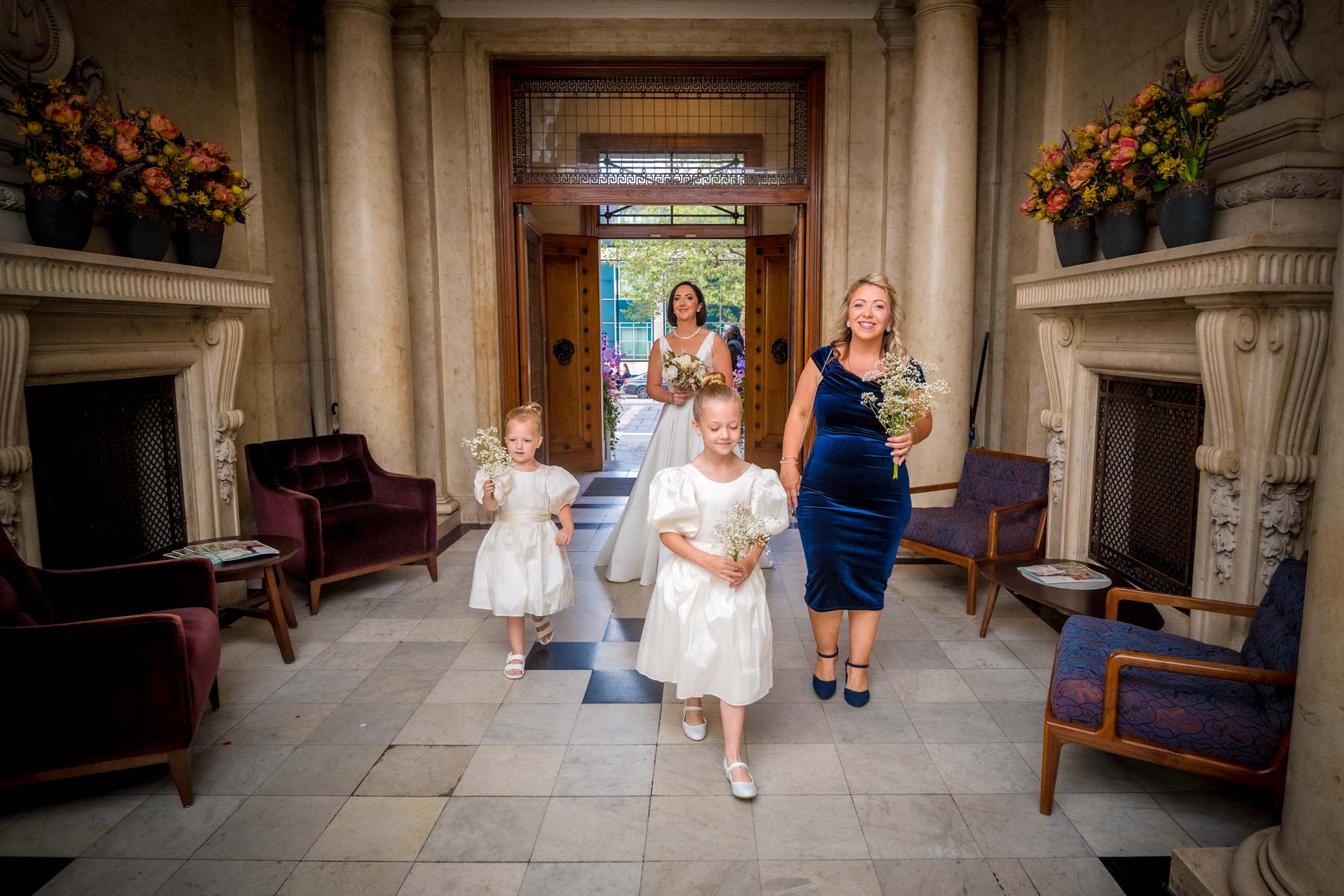 The bride arrives for her wedding with her duaghters and friend through the entrance of the Old Marylebone Town Hall