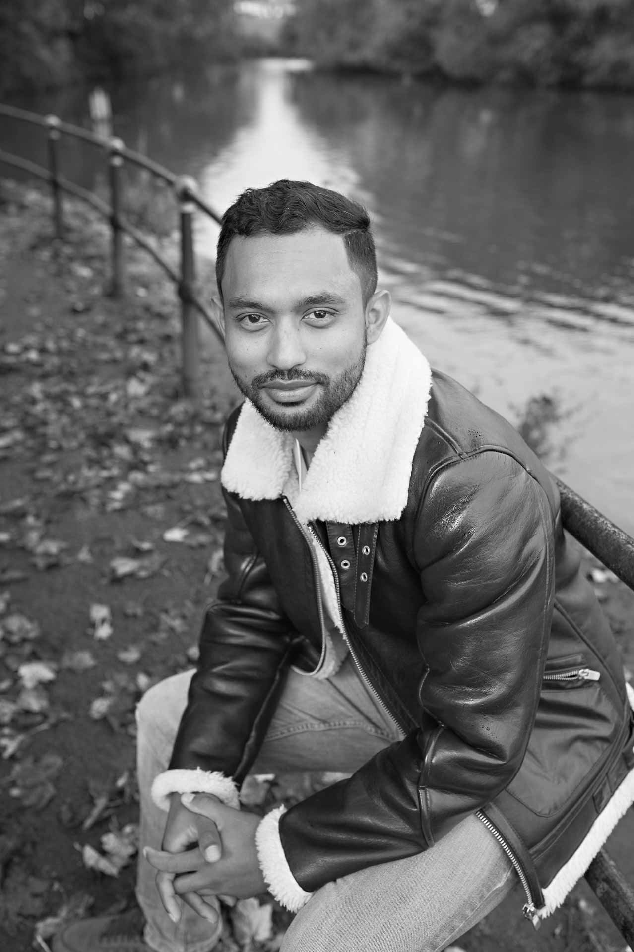 Asian male oses for photo shoot sitting on railing holding hands together