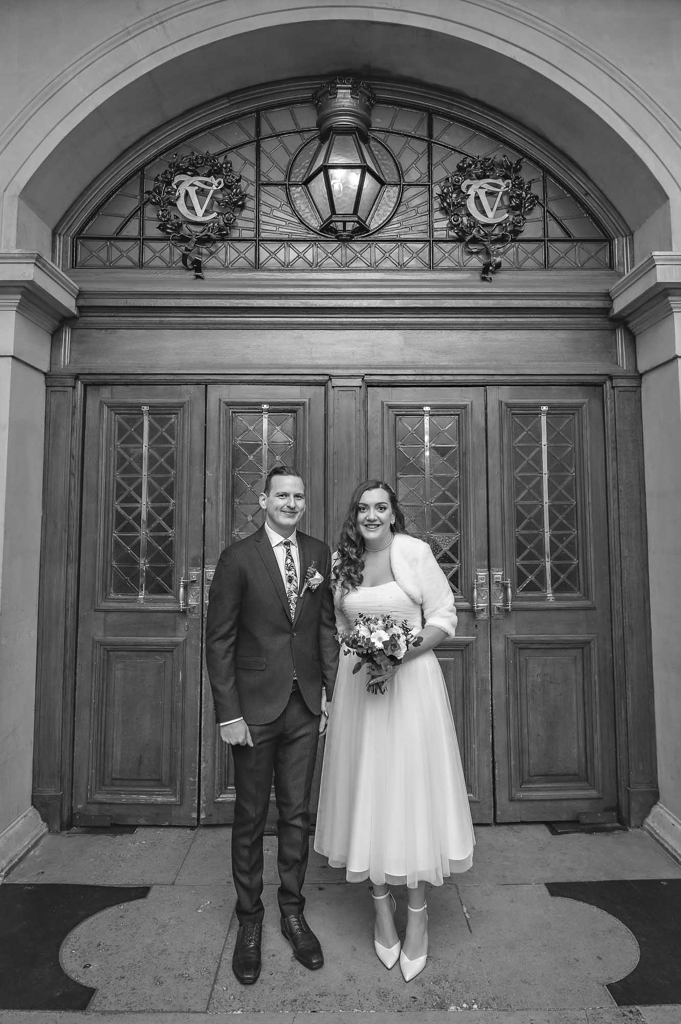 Couple standing inside doors of Cardiff City Hall after arriving for their wedding ceremony