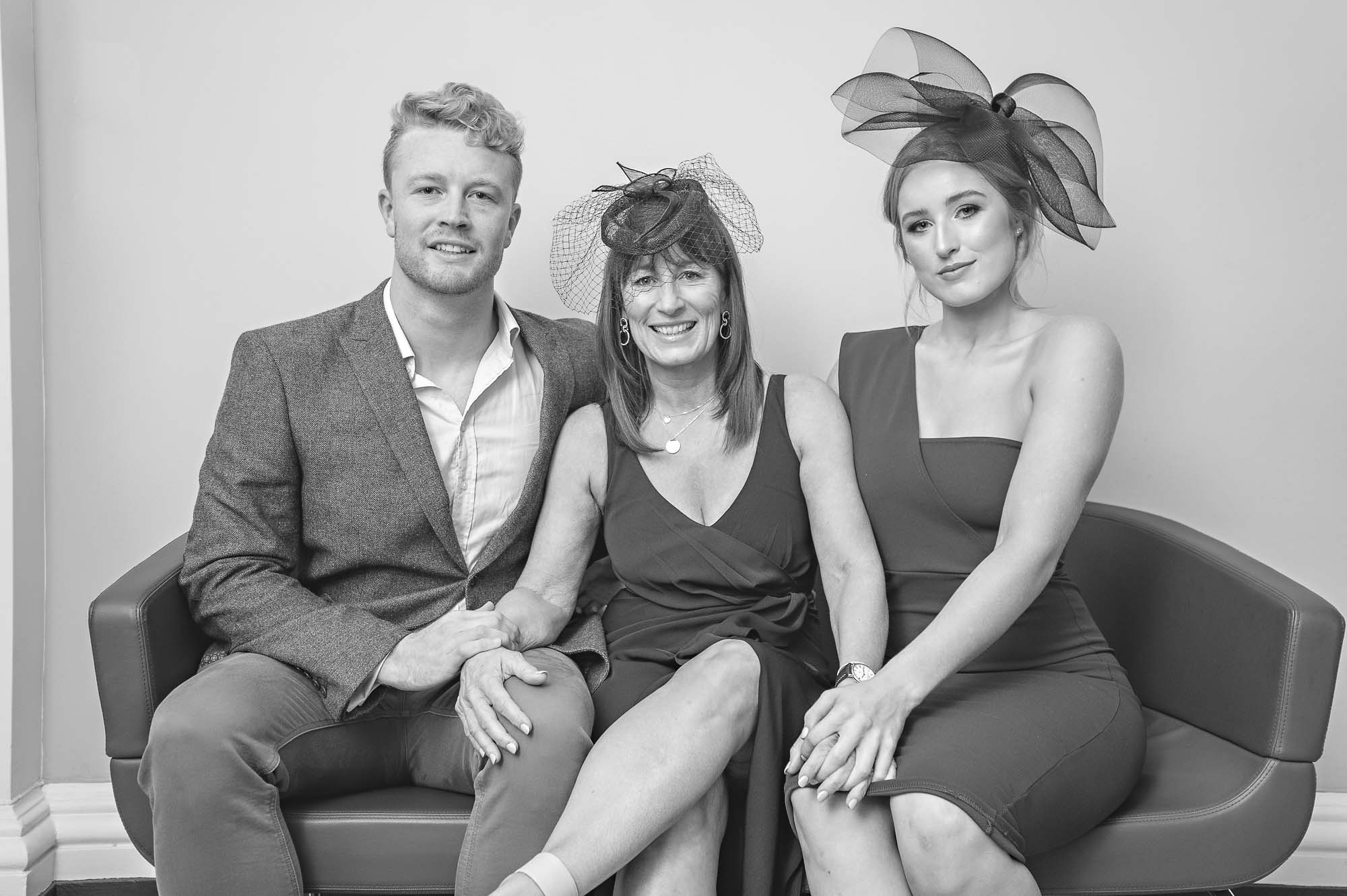 Three wedding guests sitting on short sofa before wedding