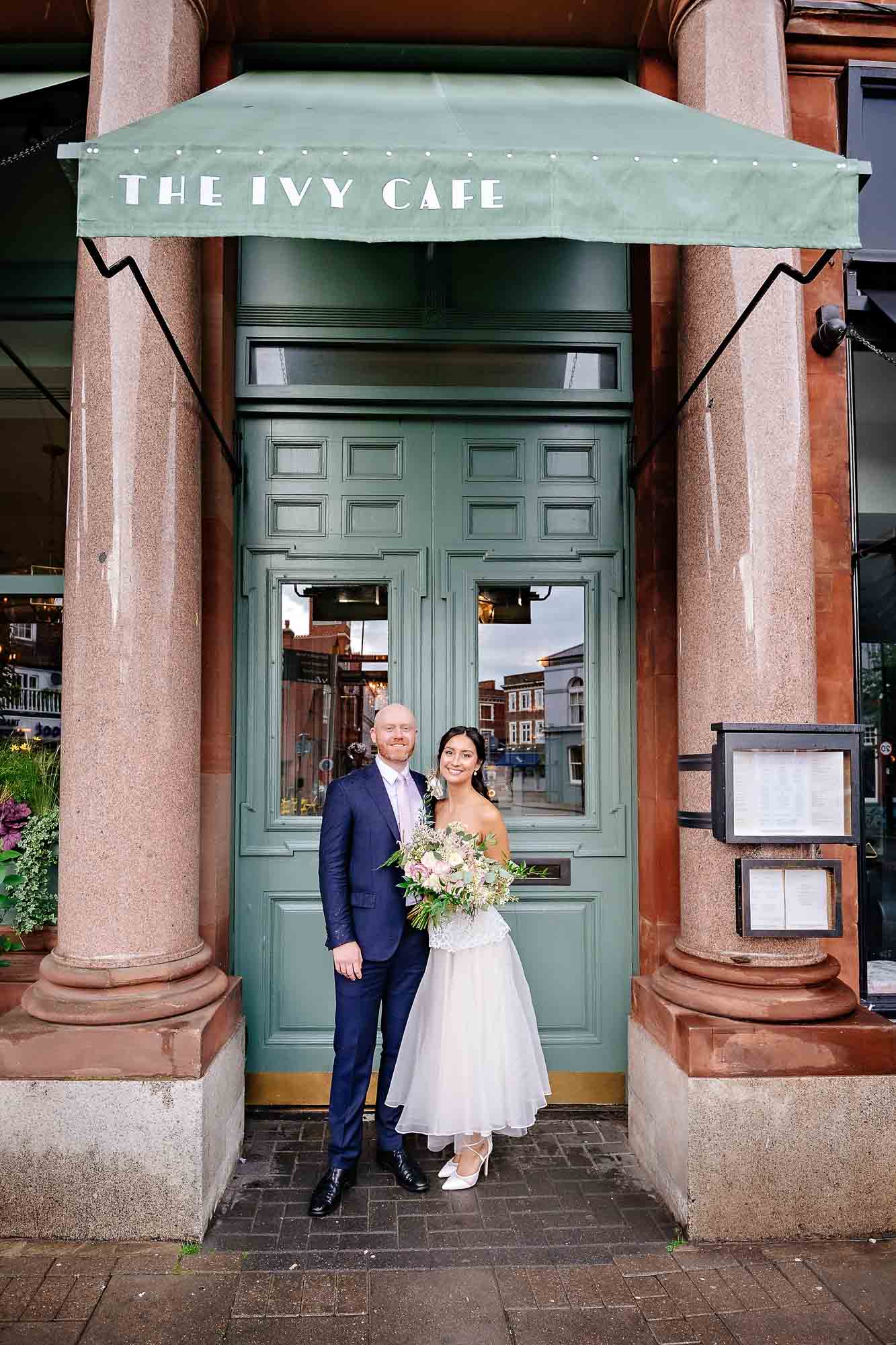Couple standing outside the Ivy Cafe in Wimbledon before their wedding reception